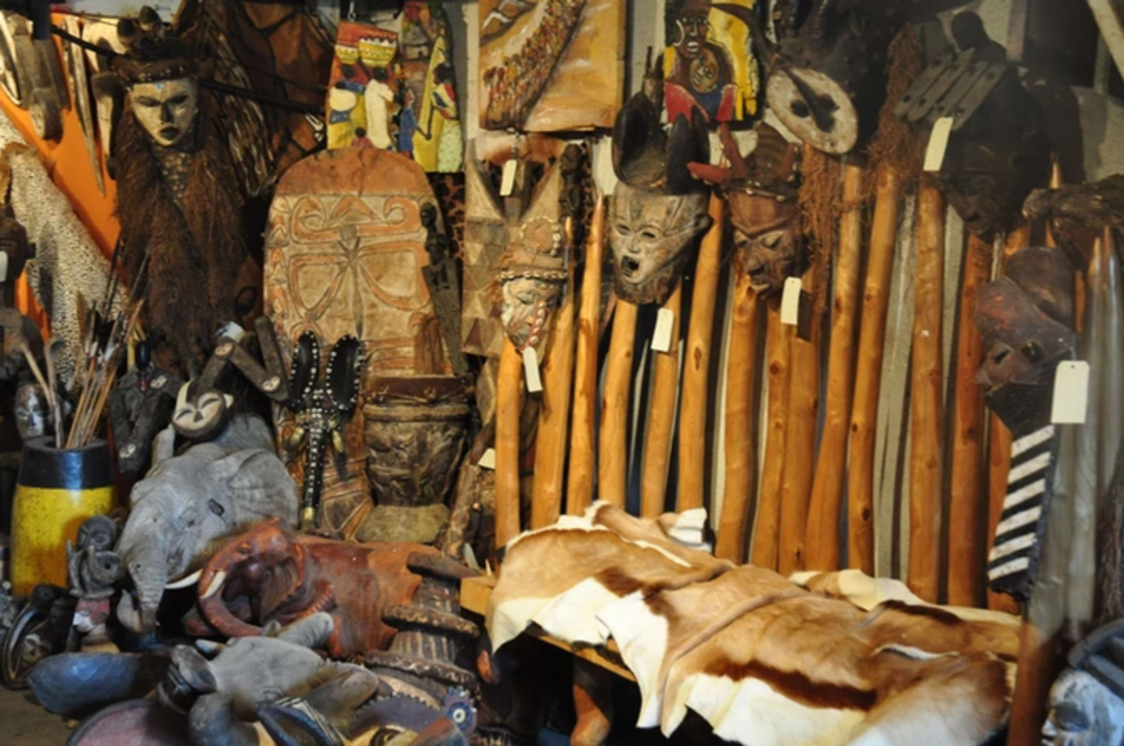 A collection of African artifacts, including masks, wooden sculptures, and animal hides displayed in a room.