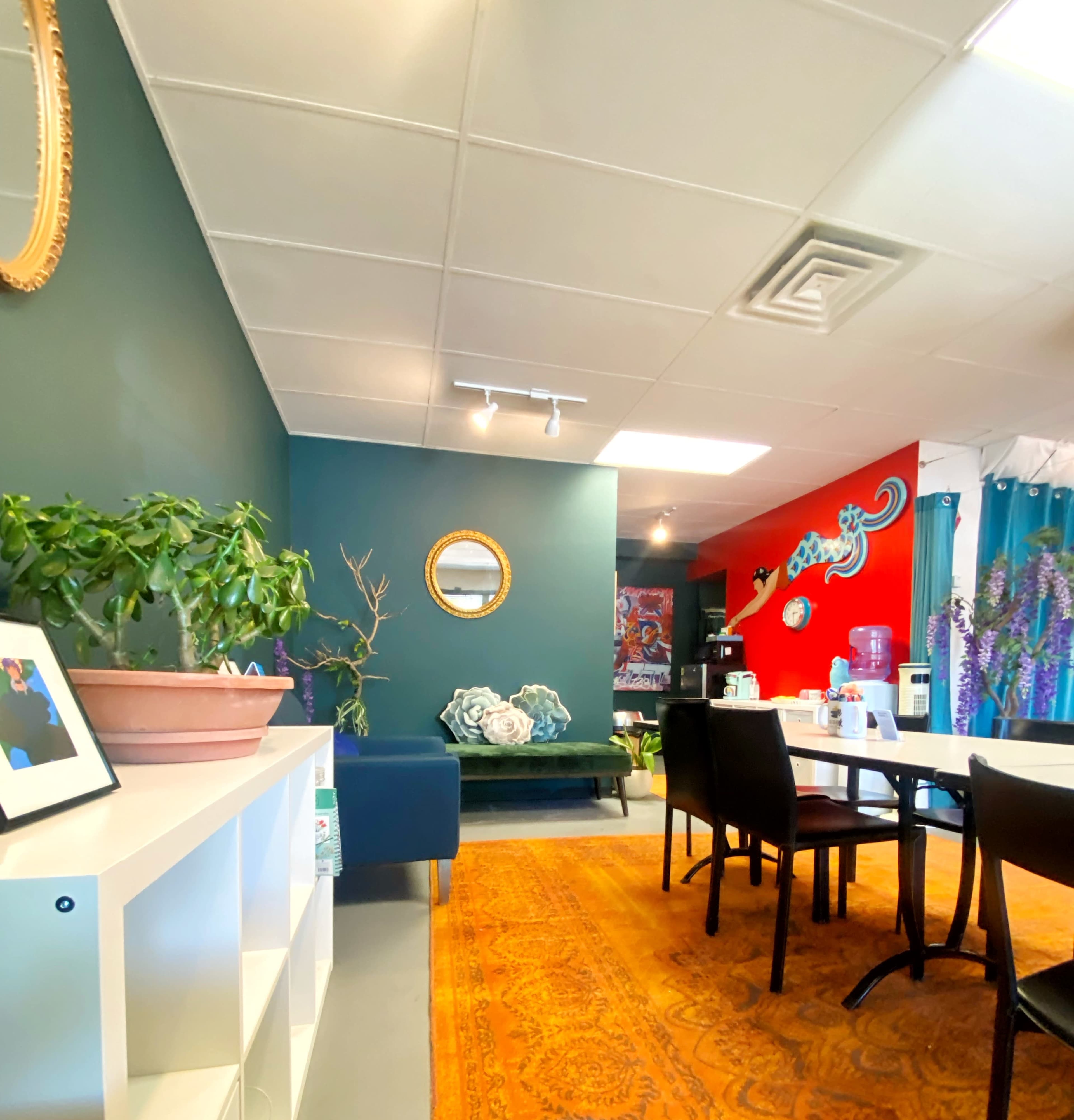 An interior space featuring a mix of colorful walls, a seating area with a blue couch, and a dining table set up with chairs.