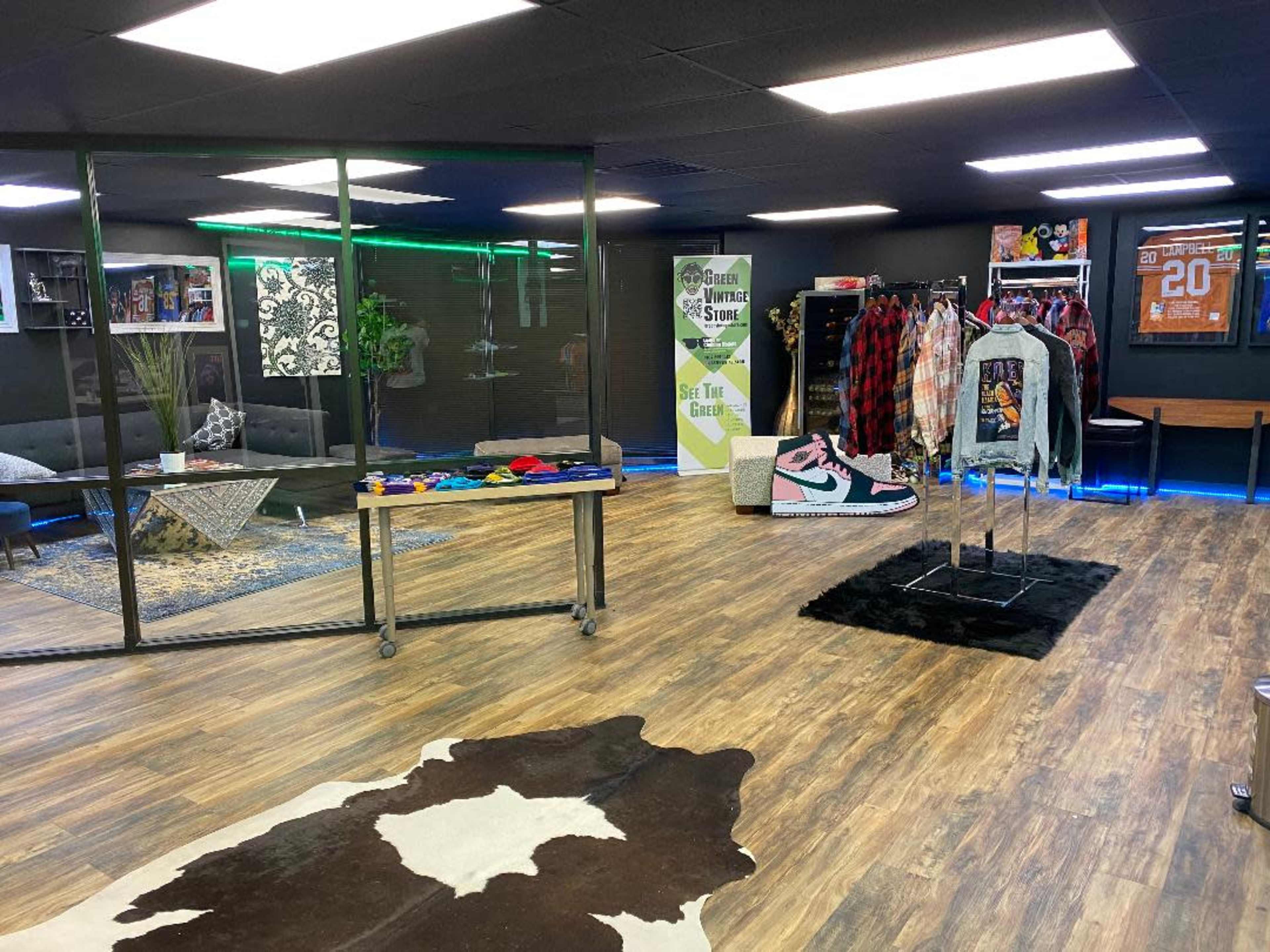 A boutique interior featuring clothing racks, a display table with vibrant items, and a cozy seating area, all illuminated by modern lighting.