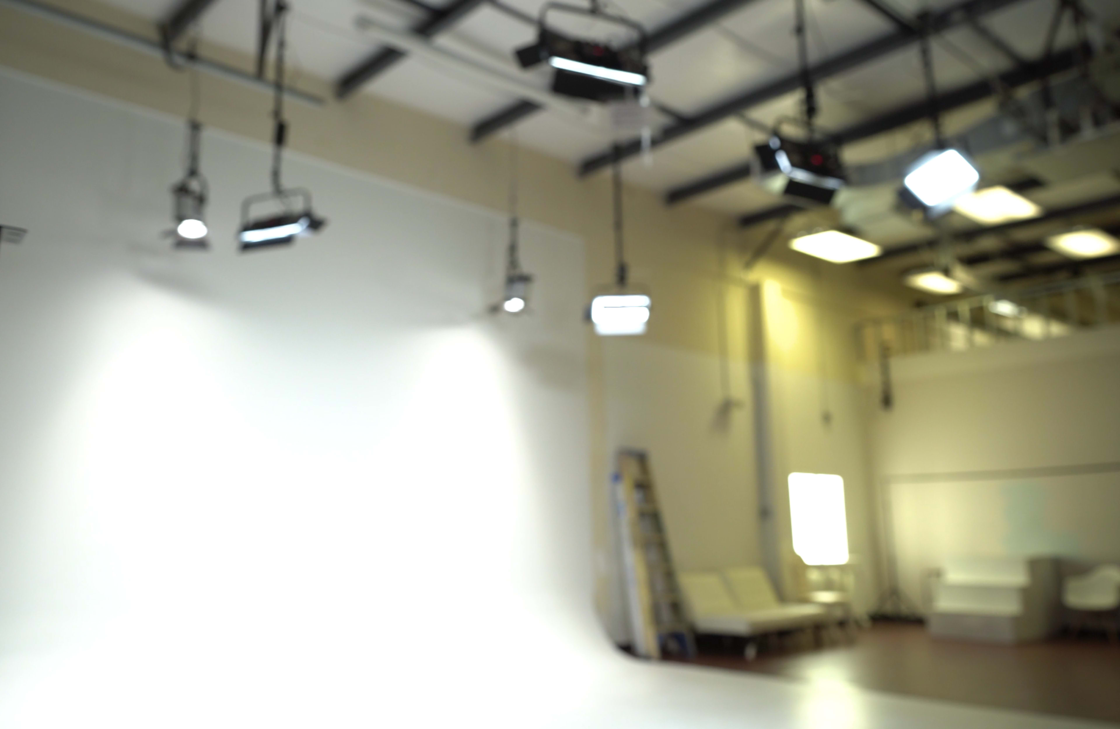 A brightly lit studio with various overhead lights and a white backdrop.