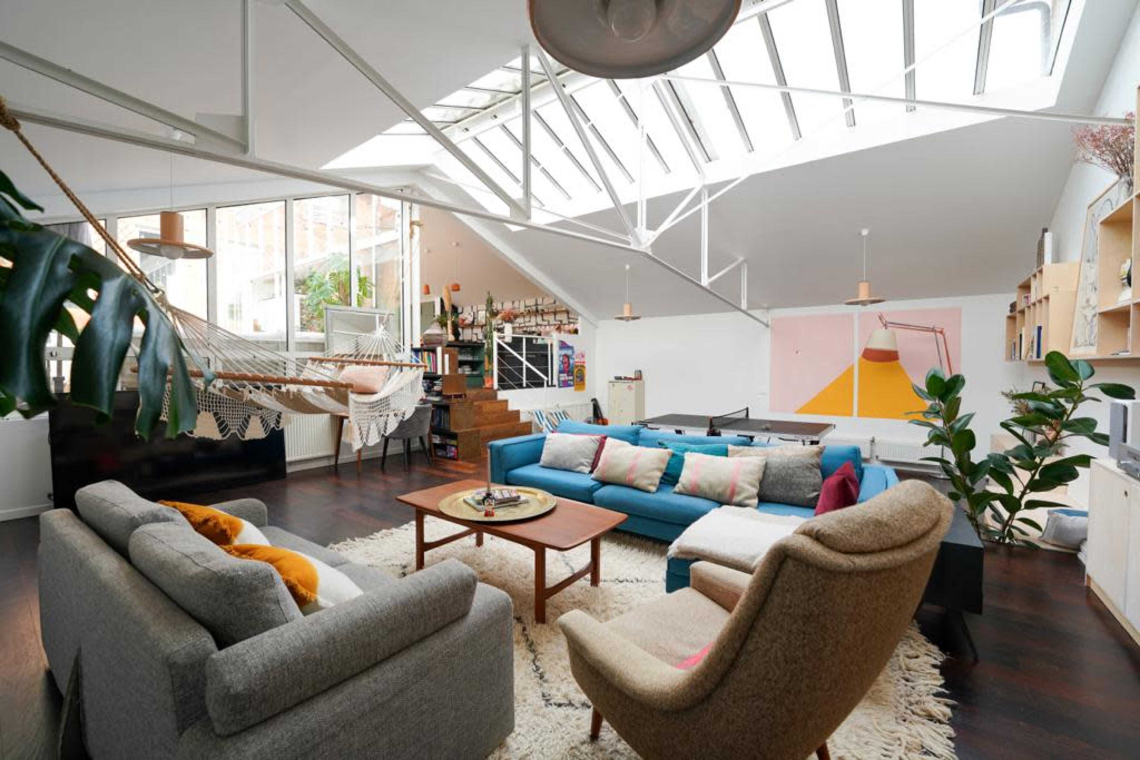 A spacious, modern living area with a mix of seating arrangement, large windows, and decorative plants.