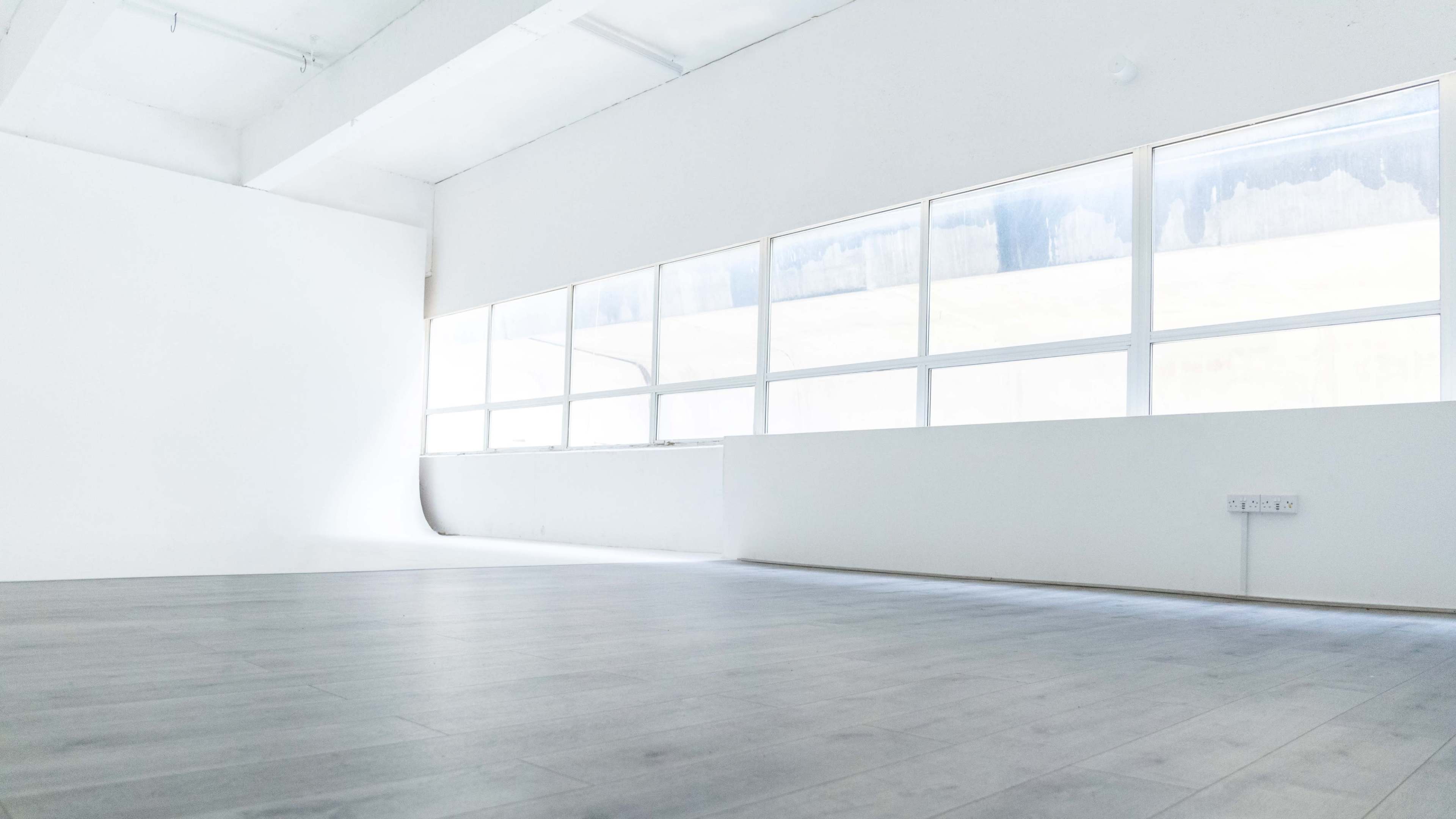 A spacious, empty room with large windows allowing natural light to enter.
