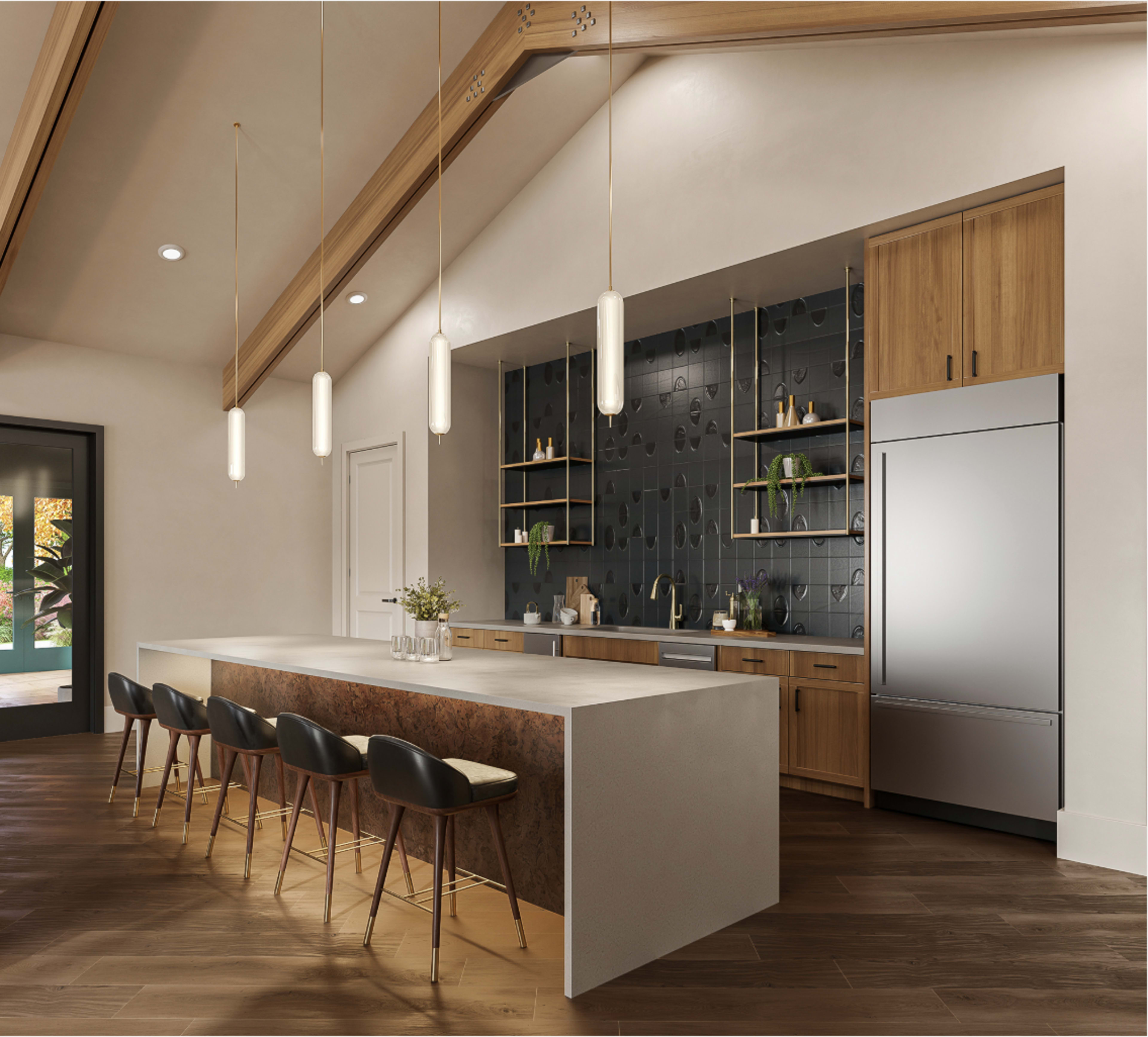 The image shows a modern kitchen featuring a large island with seating, wooden cabinetry, and a backdrop of dark textured tiles.