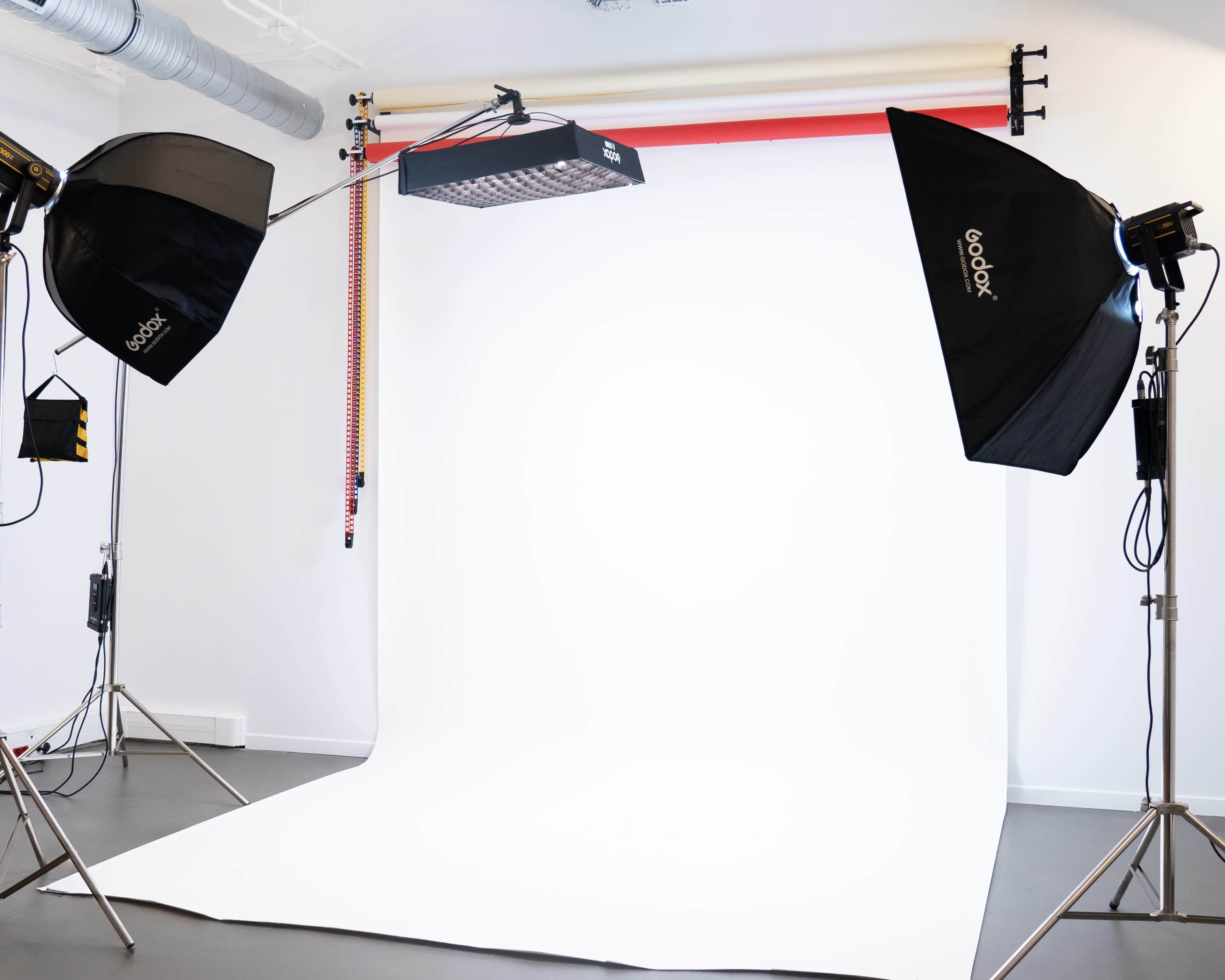 The image shows a photography studio setup with two softbox lights and a backdrop positioned on the floor.