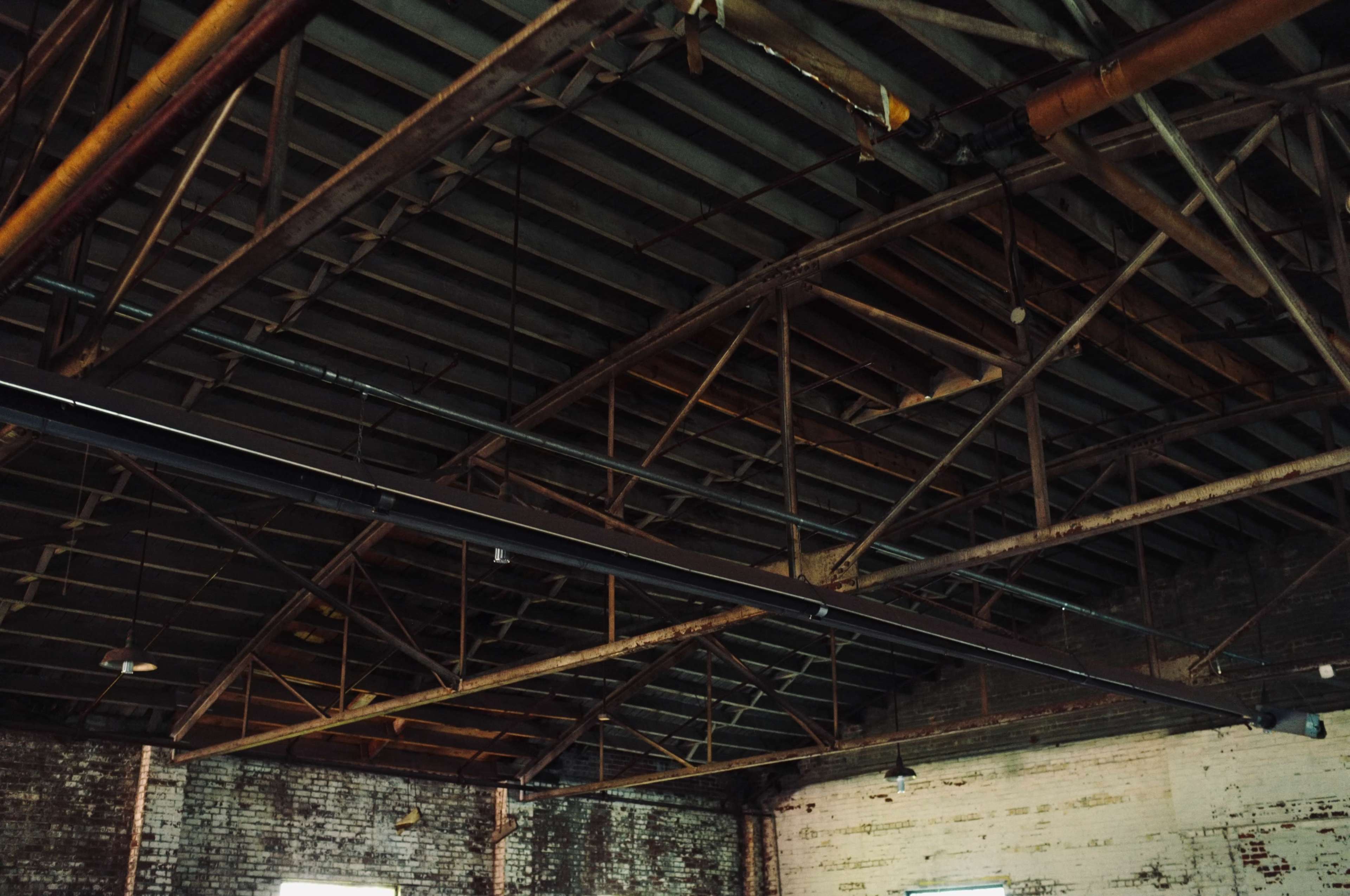 The image shows the interior of an industrial building with exposed brick walls and a metal truss ceiling.