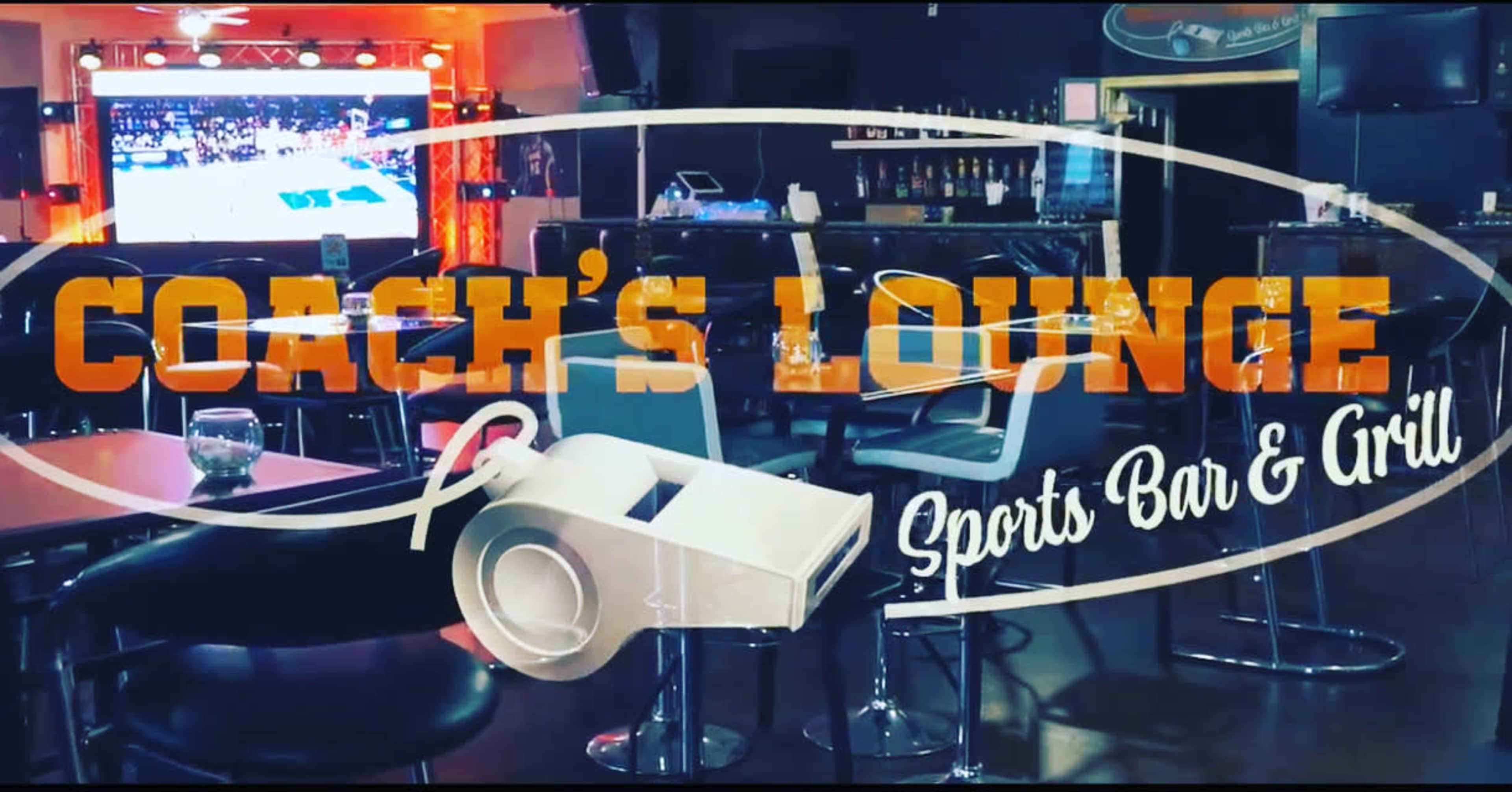 The interior of Coach's Lounge, a sports bar and grill, featuring a large screen displaying a sports event.