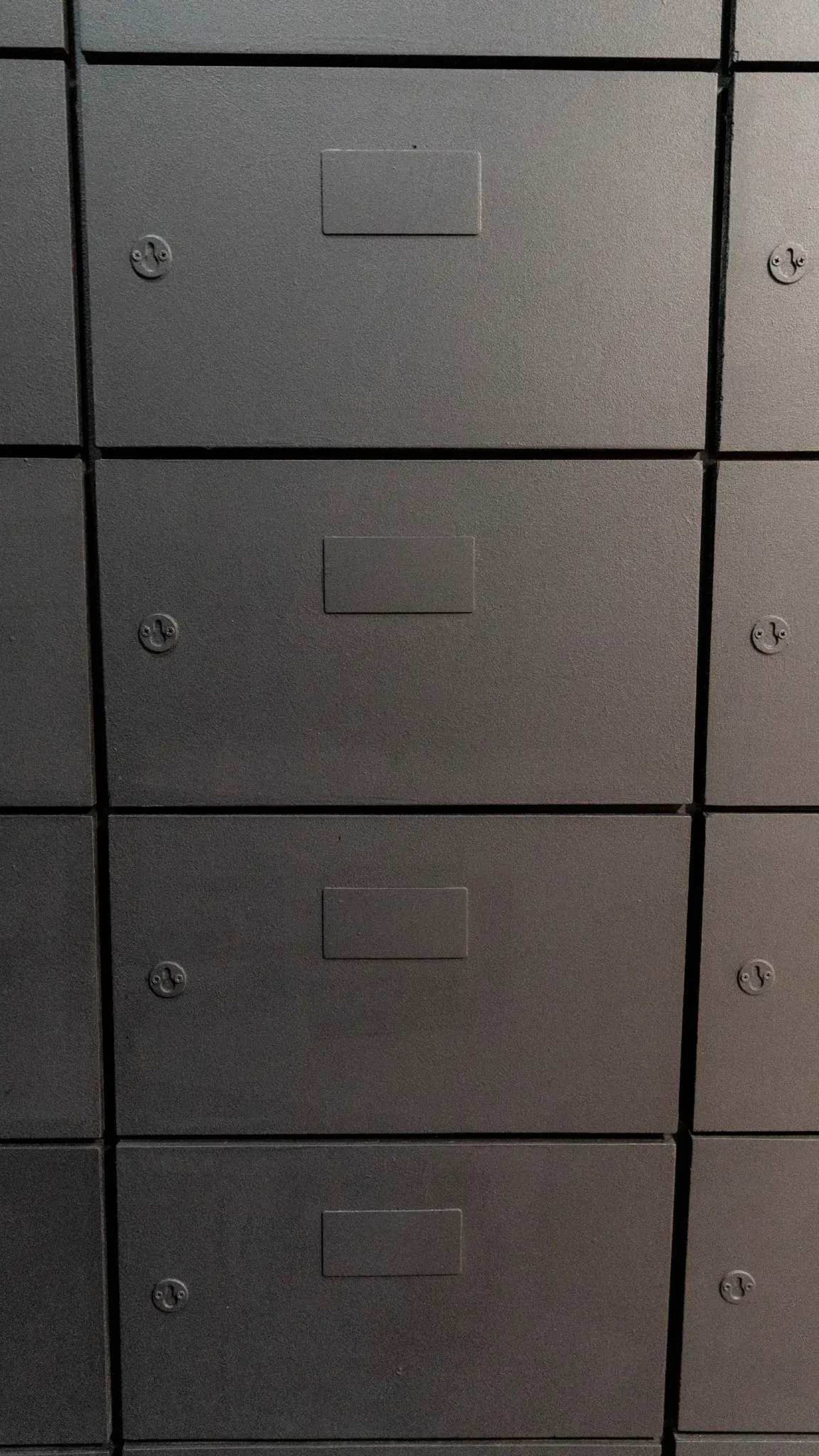The image shows a series of four black metal storage drawers lined up vertically, each with a label holder on the front.