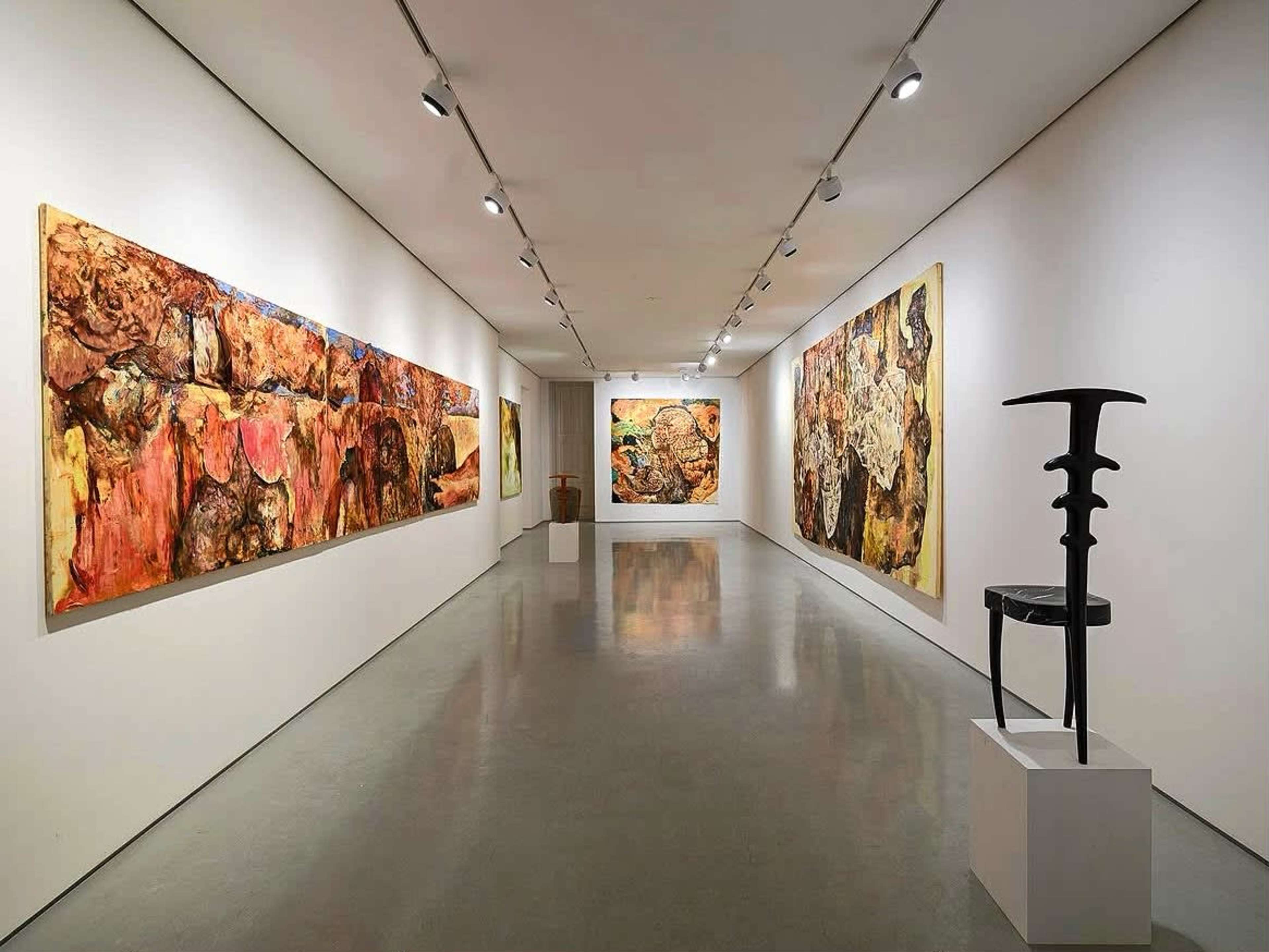 The image shows an art gallery with two large abstract paintings on the walls and a sculpture displayed on a pedestal in the center.