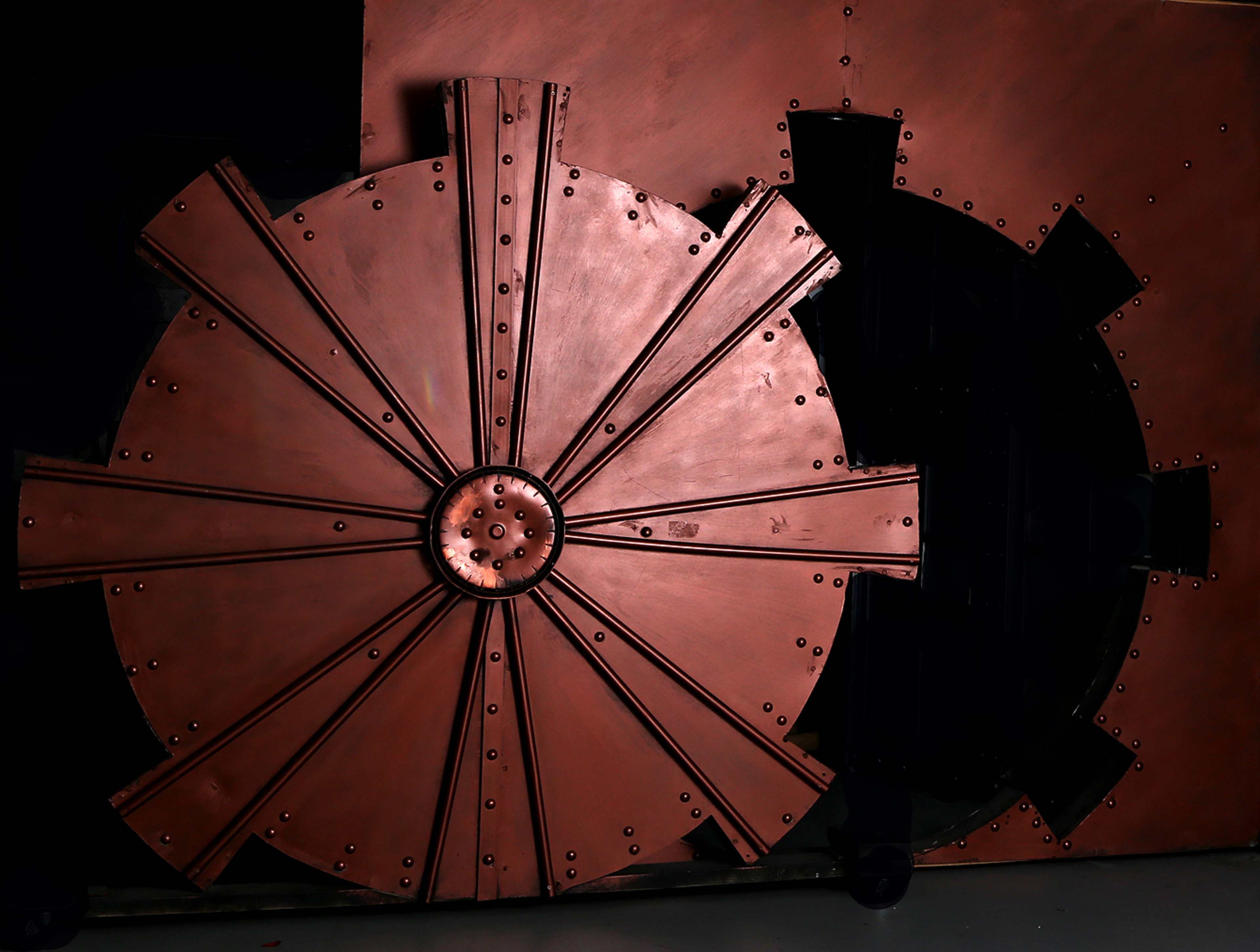 Two large, circular gears with a metallic finish, one in copper and the other in black, placed against a dark background.