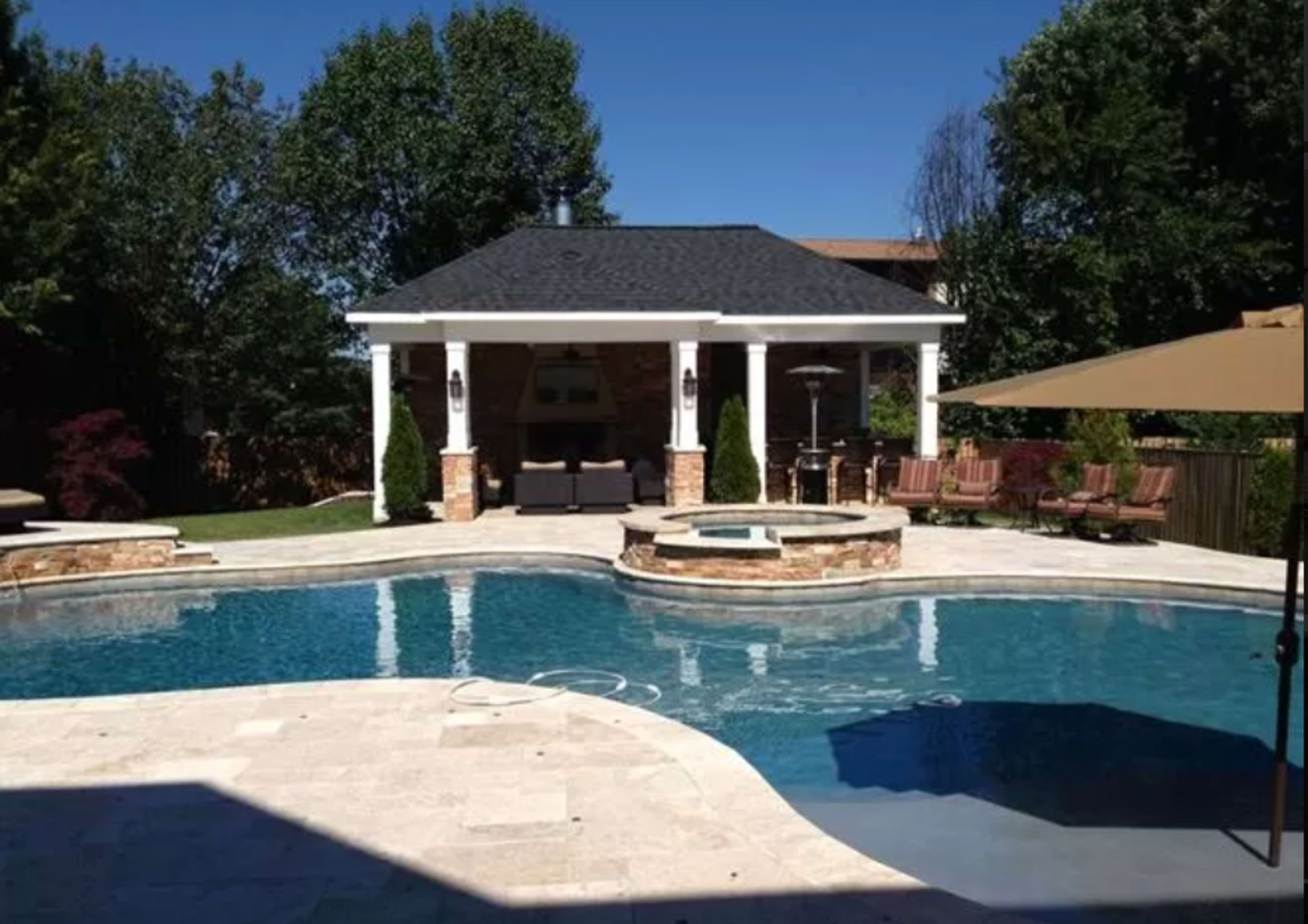 A landscaped backyard with a swimming pool, a patio structure, and lounge chairs under shade.