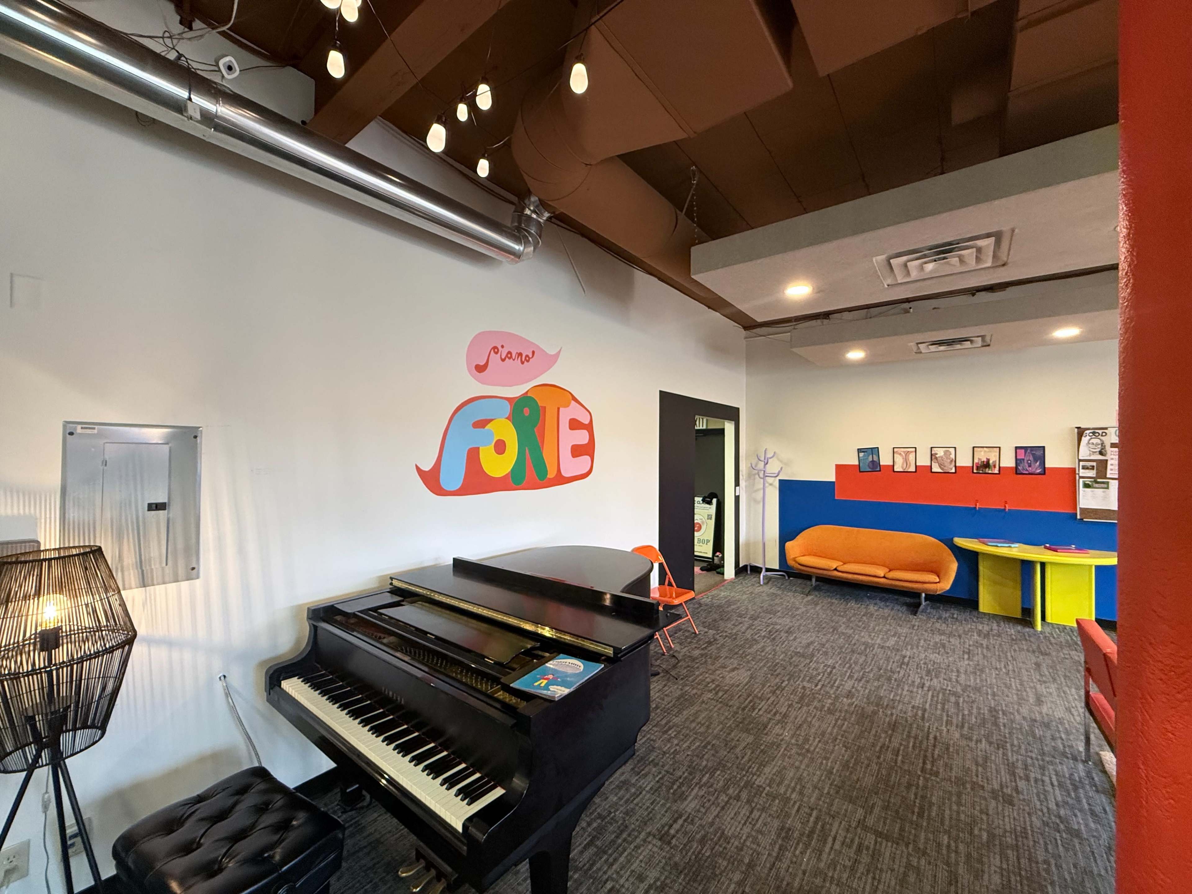 The image shows a brightly colored room featuring a black piano, an orange couch, and colorful walls with the word "FORTE" prominently displayed.