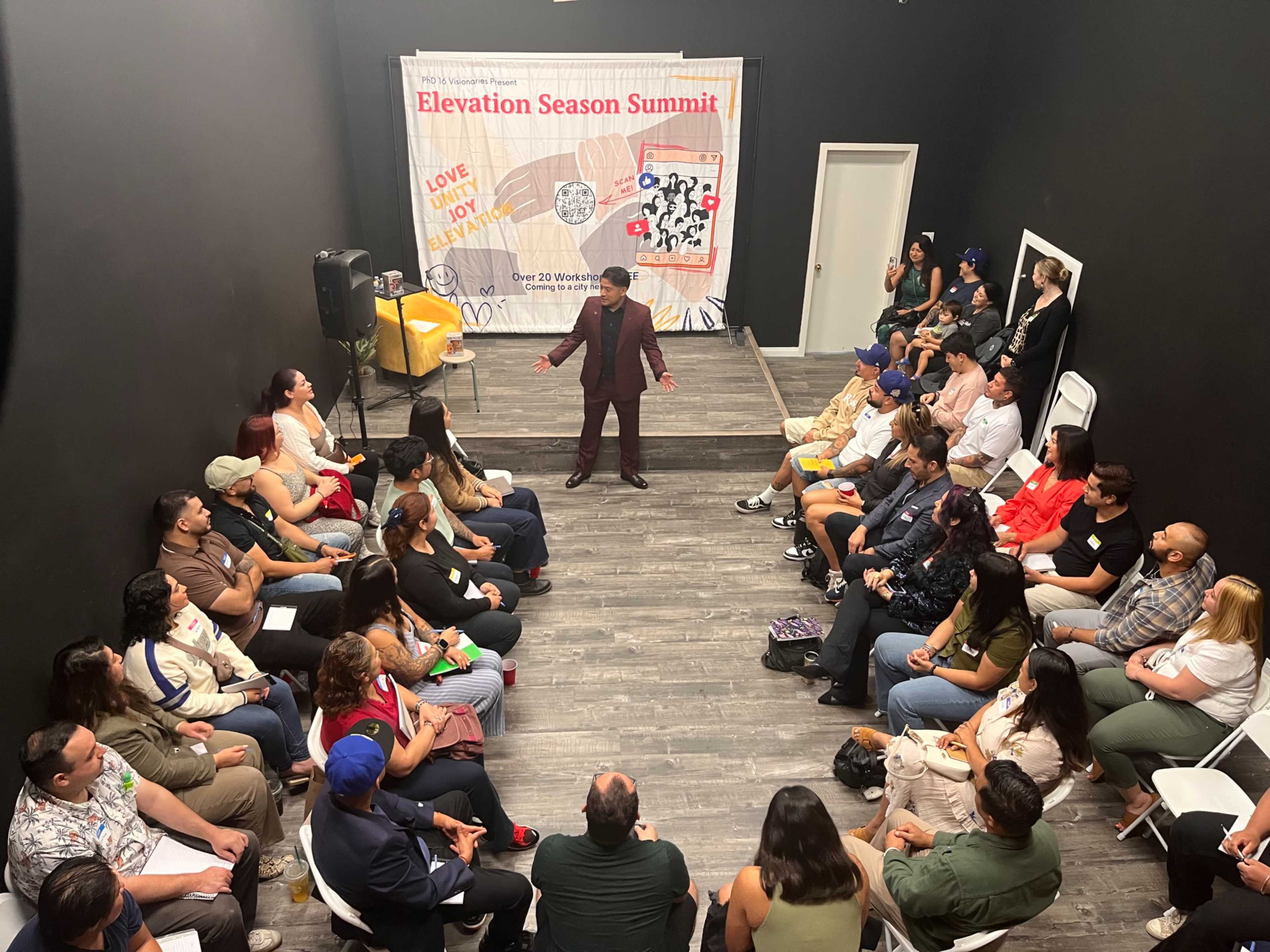 A speaker addresses an audience seated in a room during the Elevation Season Summit event.