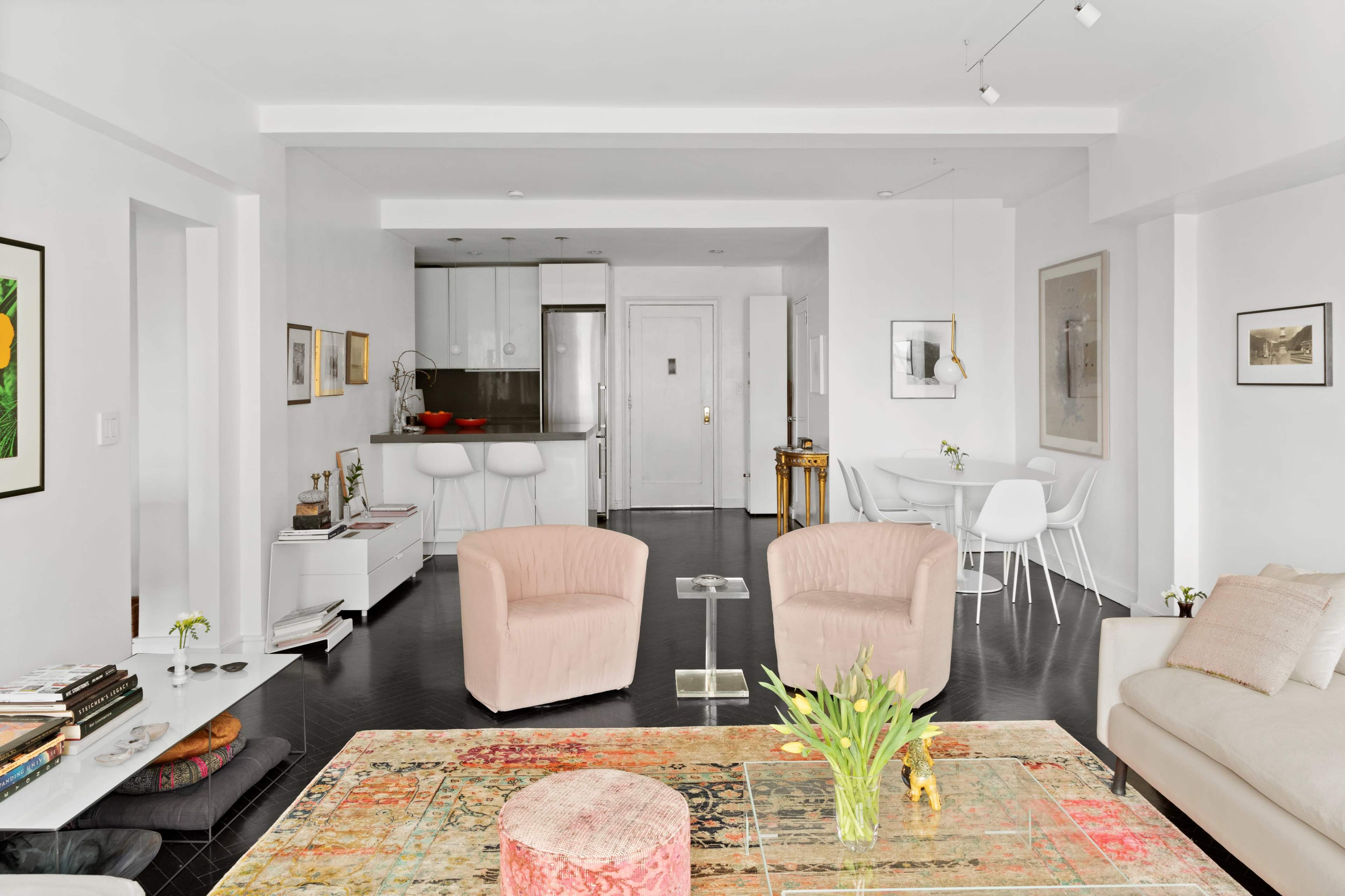 The image depicts a modern, open-concept living space with a rug, seating area, and dining area featuring minimalist furniture.