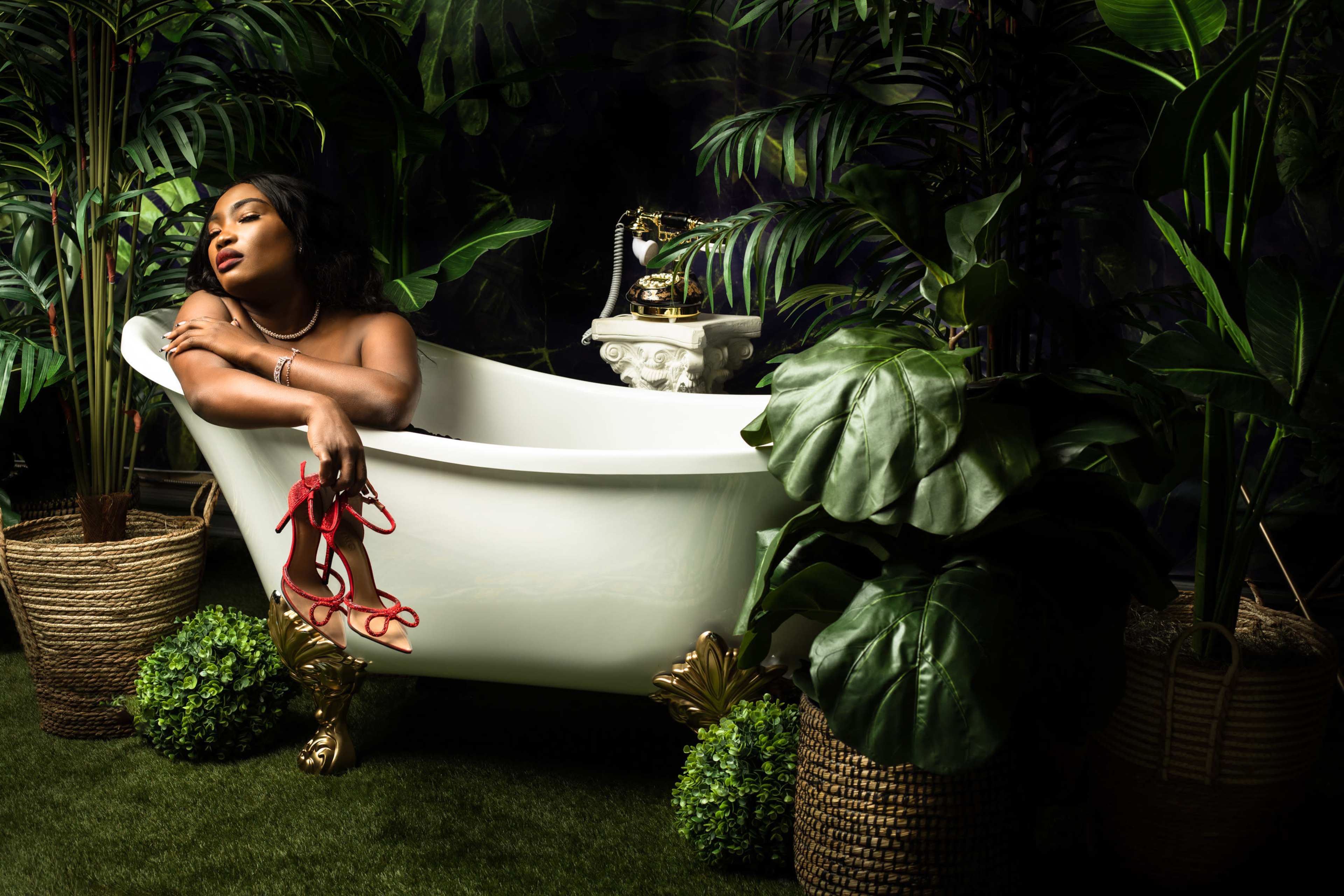 A woman reclines in a white bathtub surrounded by lush greenery and decorative plants.