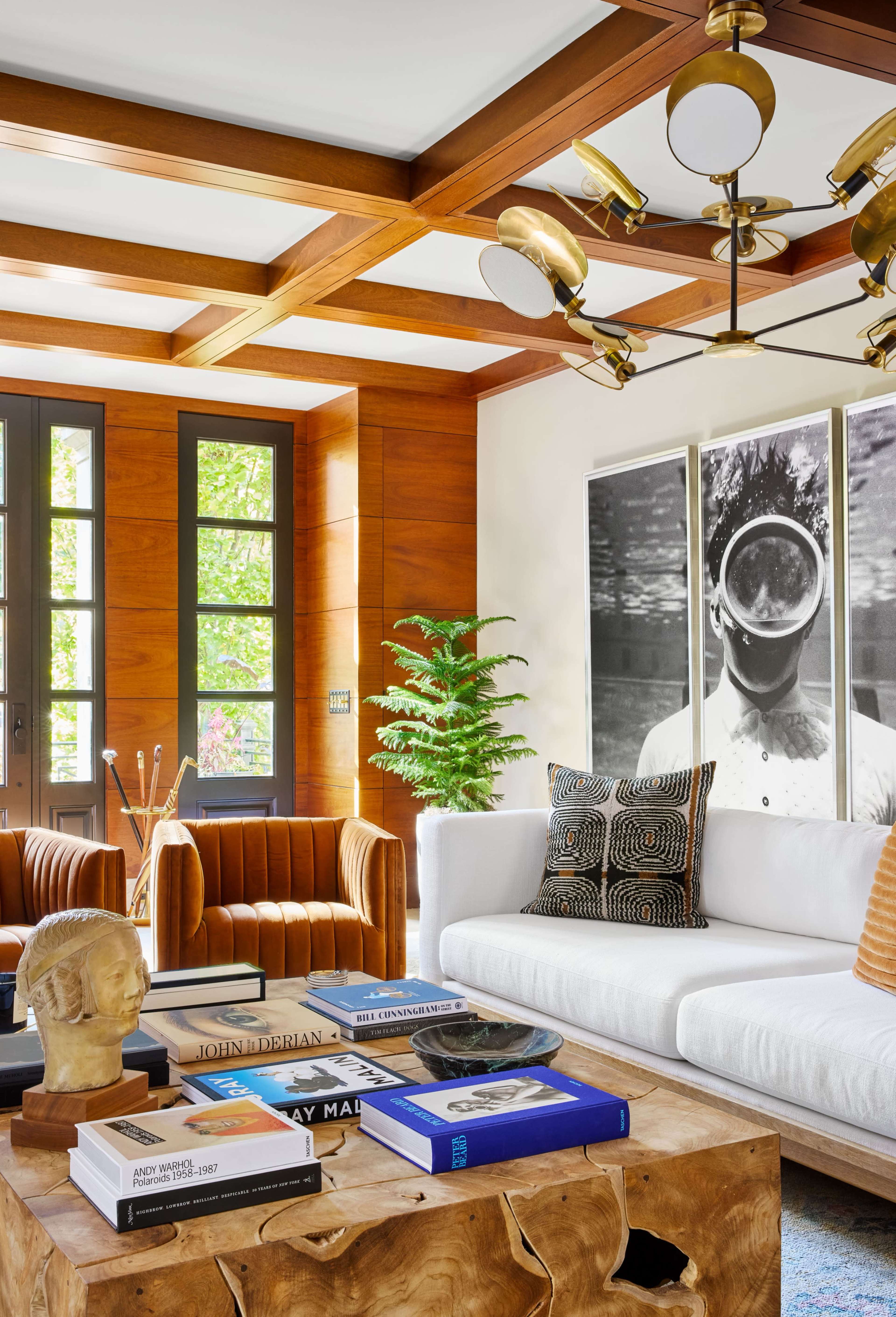 The living room features a white sofa, brown armchairs, a wooden coffee table, and two large framed photographs on the wall.