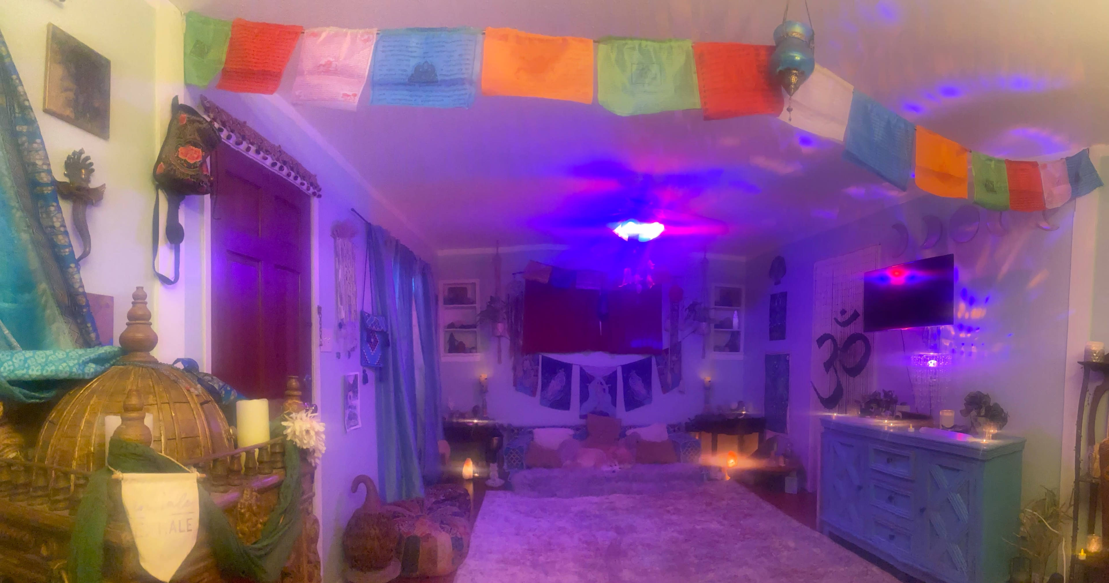 A cozy indoor space adorned with colorful prayer flags, candles, and various decorations, creating a serene atmosphere.