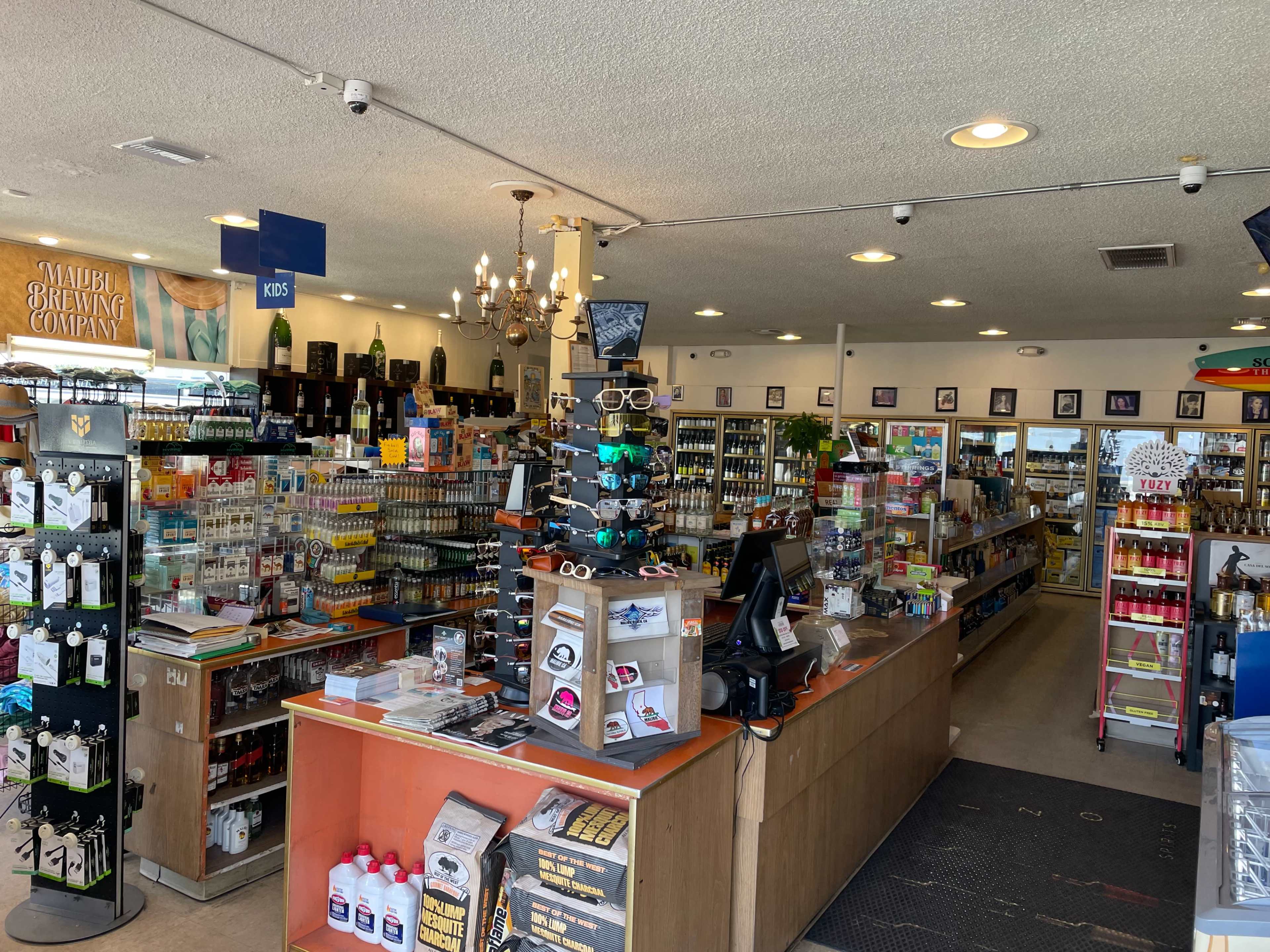 The interior of a retail store features a checkout counter surrounded by shelves stocked with beverages and various products.