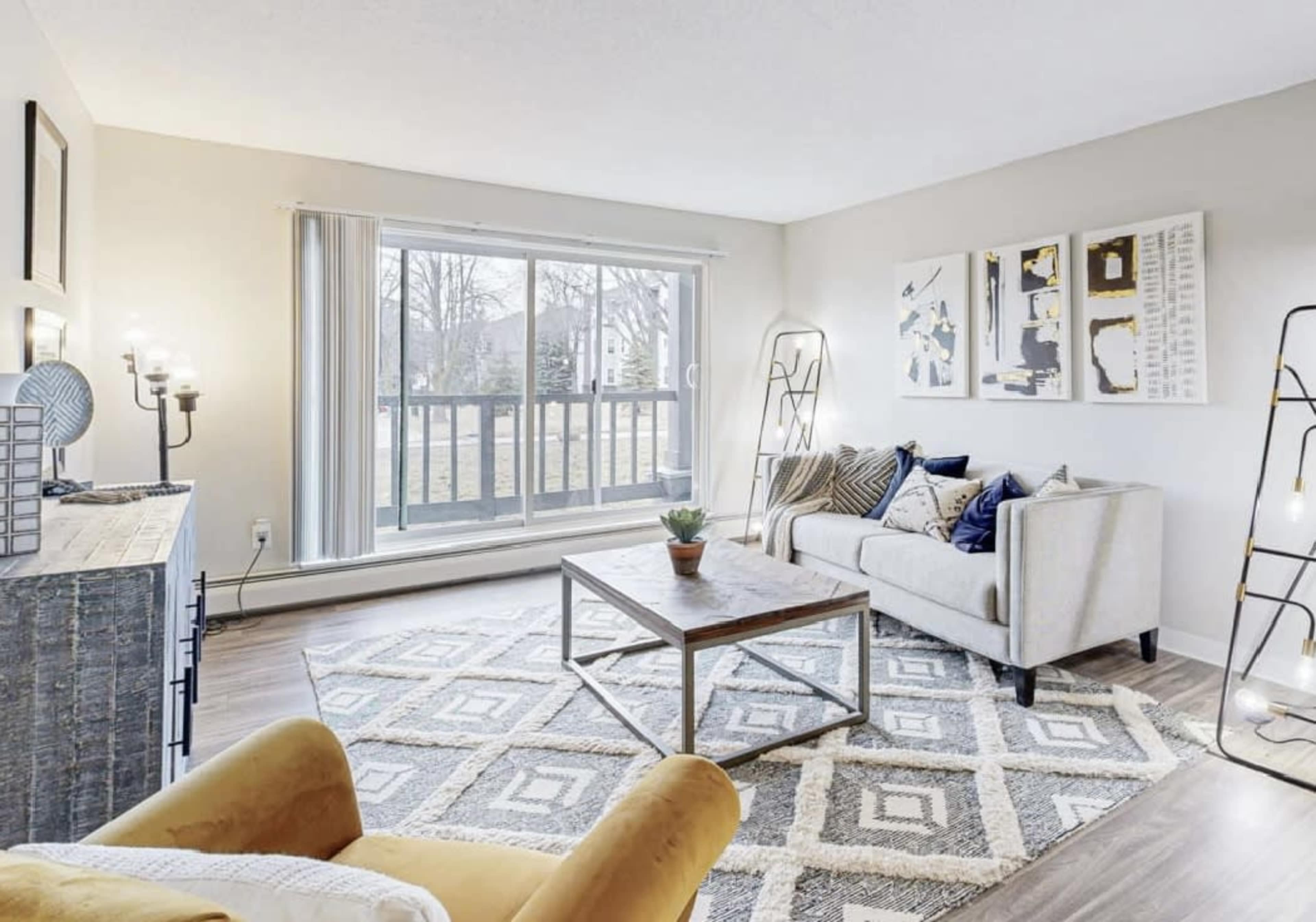 The living room features a beige sofa, a wooden coffee table, and large sliding doors leading to a balcony.