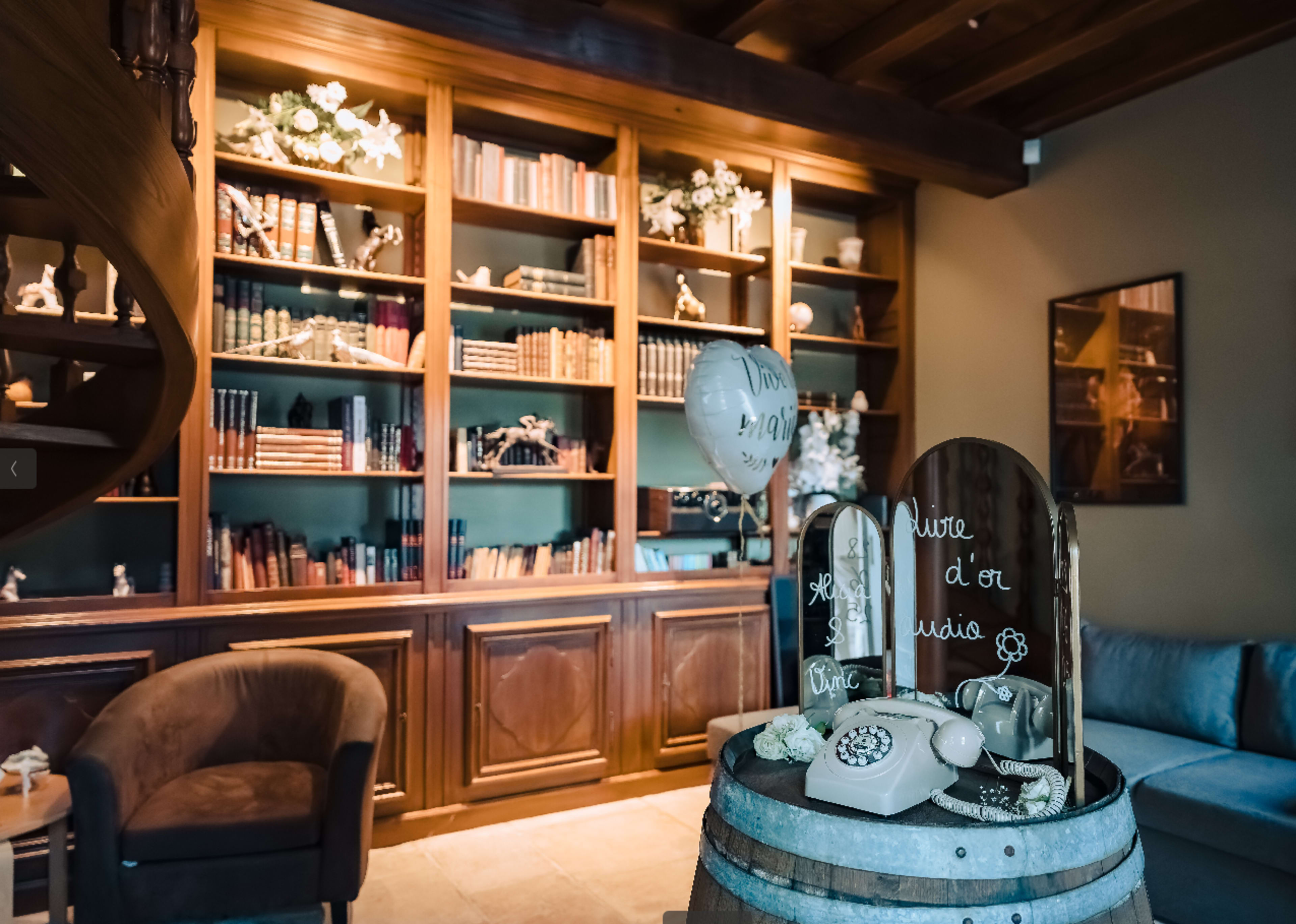 A cozy interior features a wooden bookshelf filled with books, while a decorative display with a vintage telephone and a balloon is arranged in the foreground.