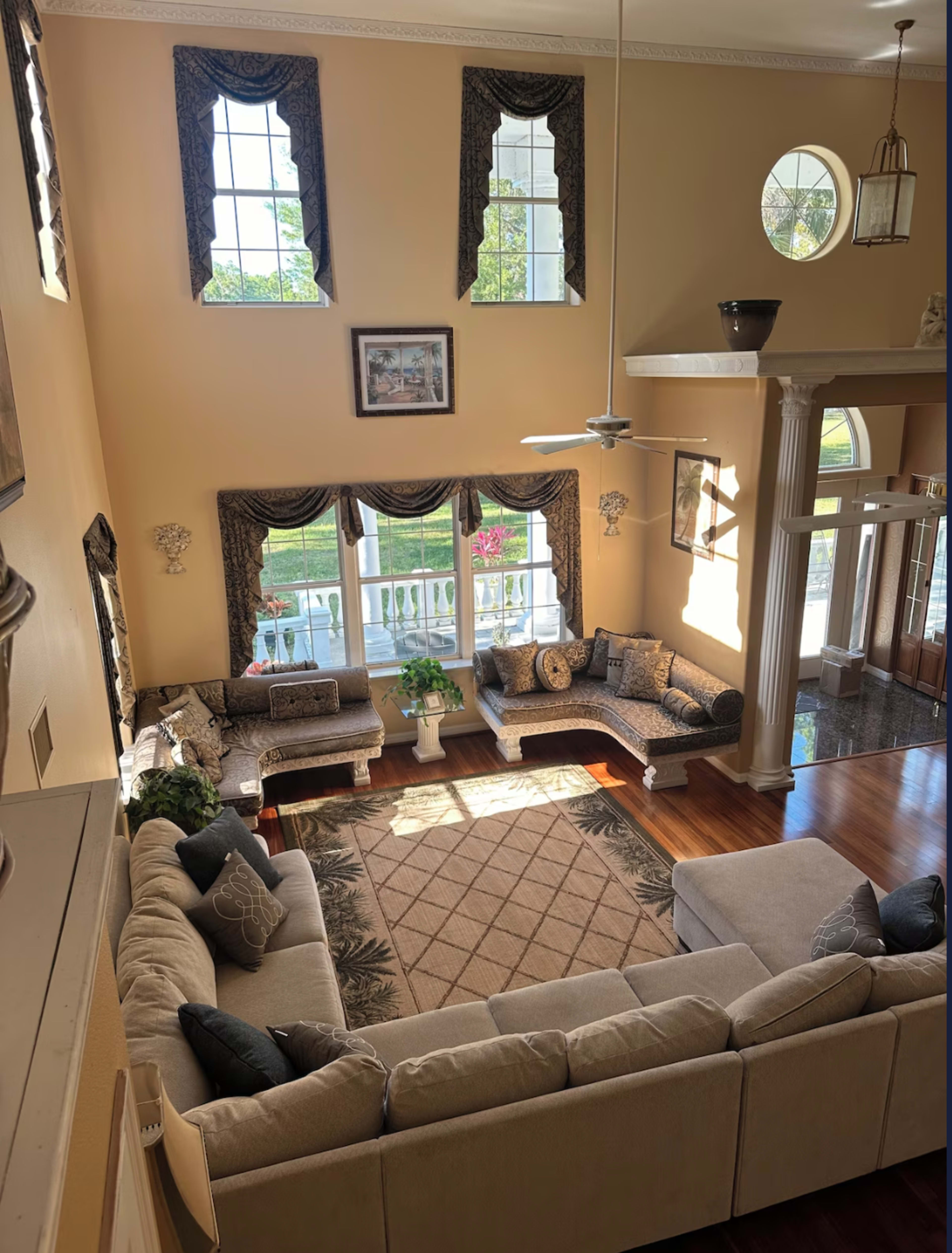 A spacious living room with large windows, a sectional sofa, and a central area rug.