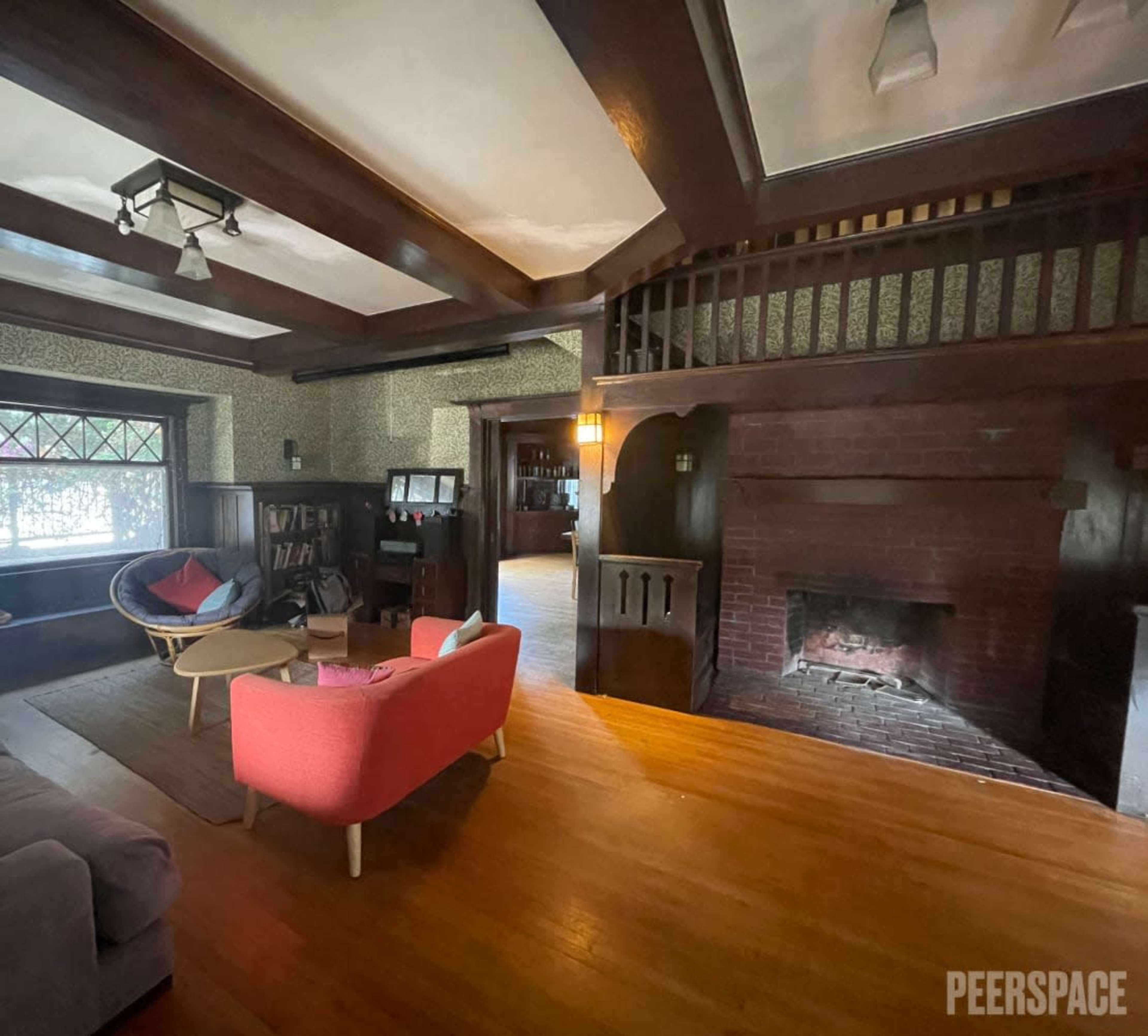 A spacious living room with wooden beams, a large fireplace, and a mix of modern and vintage furniture.