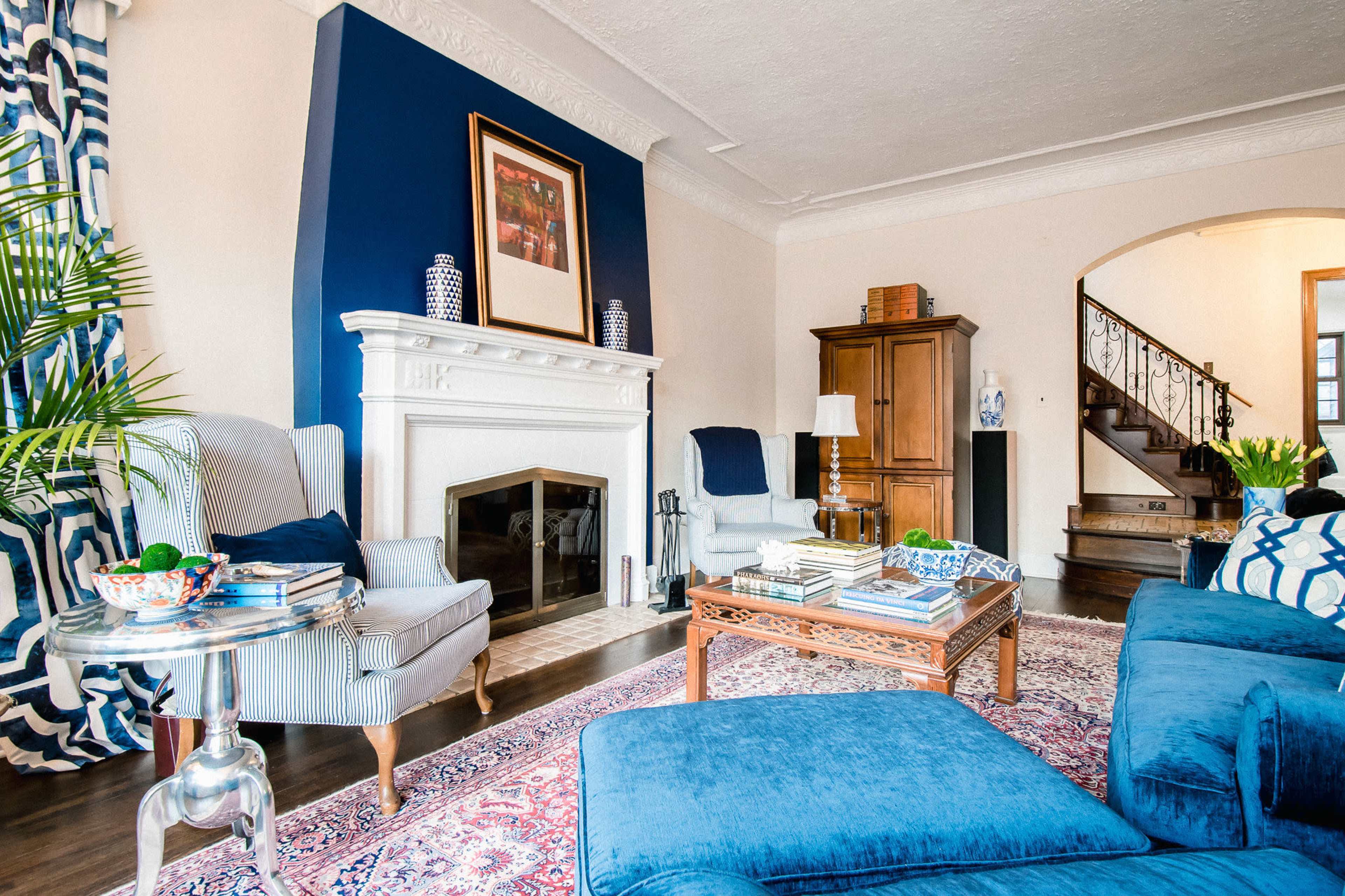 A living room featuring a blue accent wall, a white fireplace, and a mix of comfortable seating arrangements.