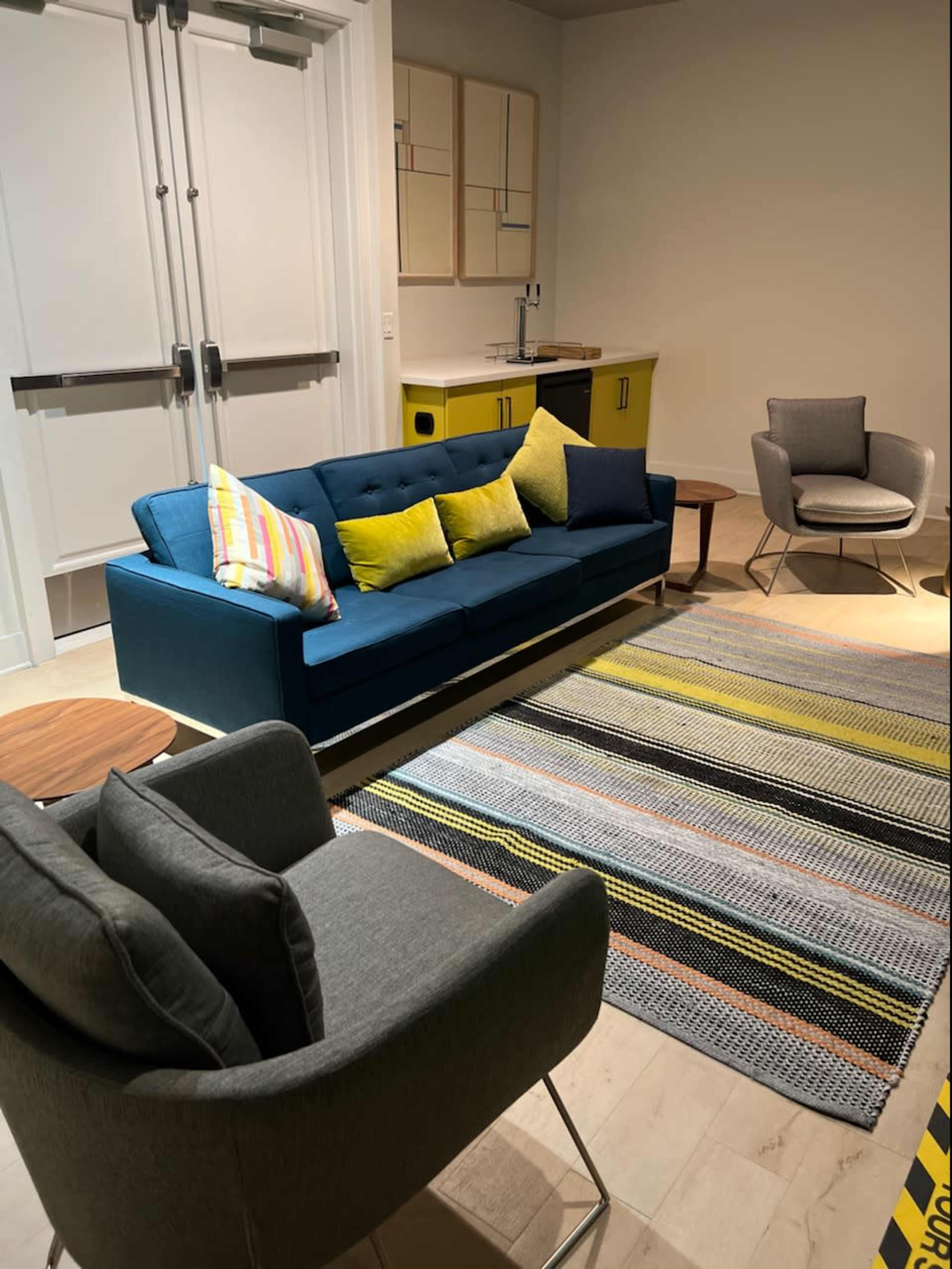 A modern living space featuring a blue sofa, a gray armchair, a round side table, and a striped area rug.