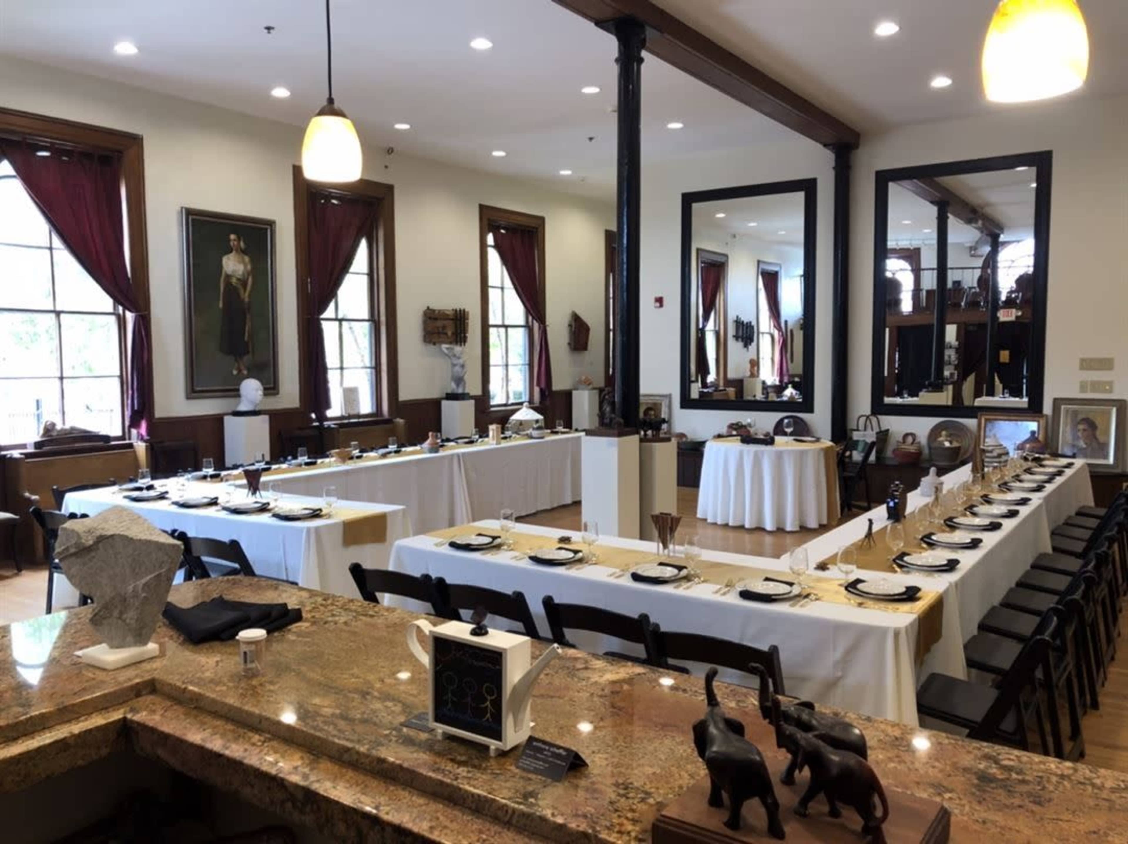 The image shows a spacious dining hall set with multiple tables arranged with tableware and decorative items.