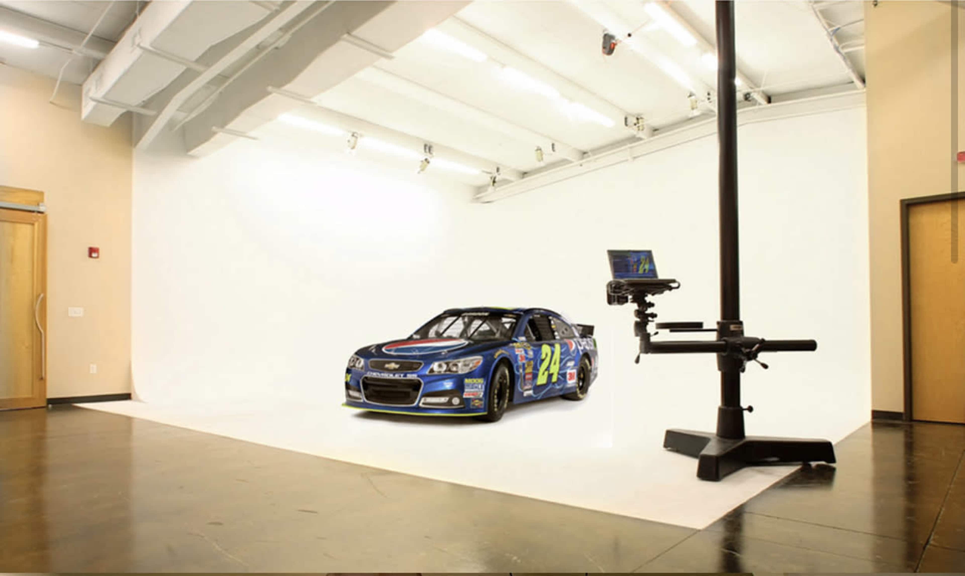 A race car is positioned on a white backdrop in a studio setting.