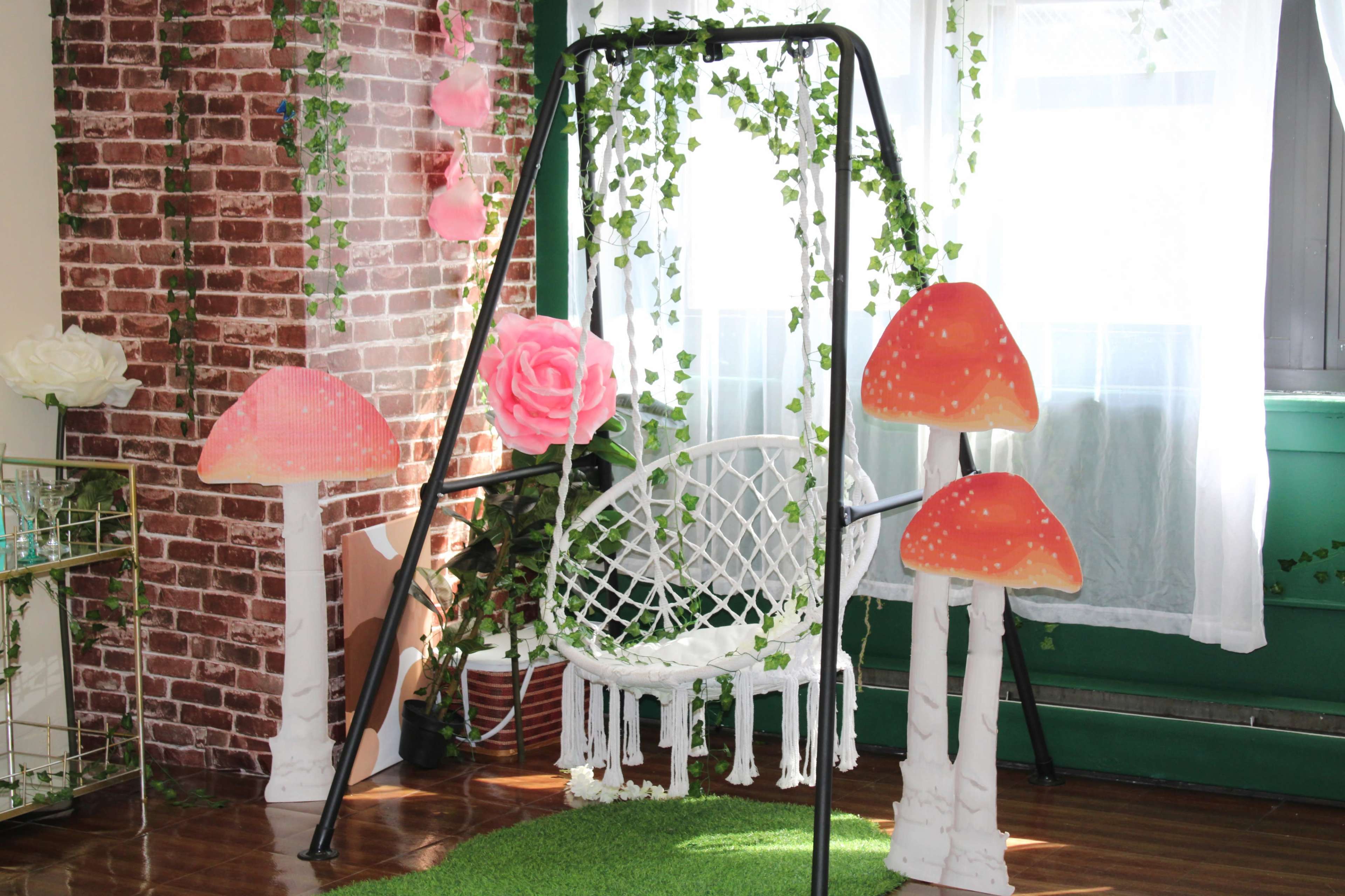 The scene features a swing surrounded by oversized mushroom decorations and green vines in a brightly lit room.