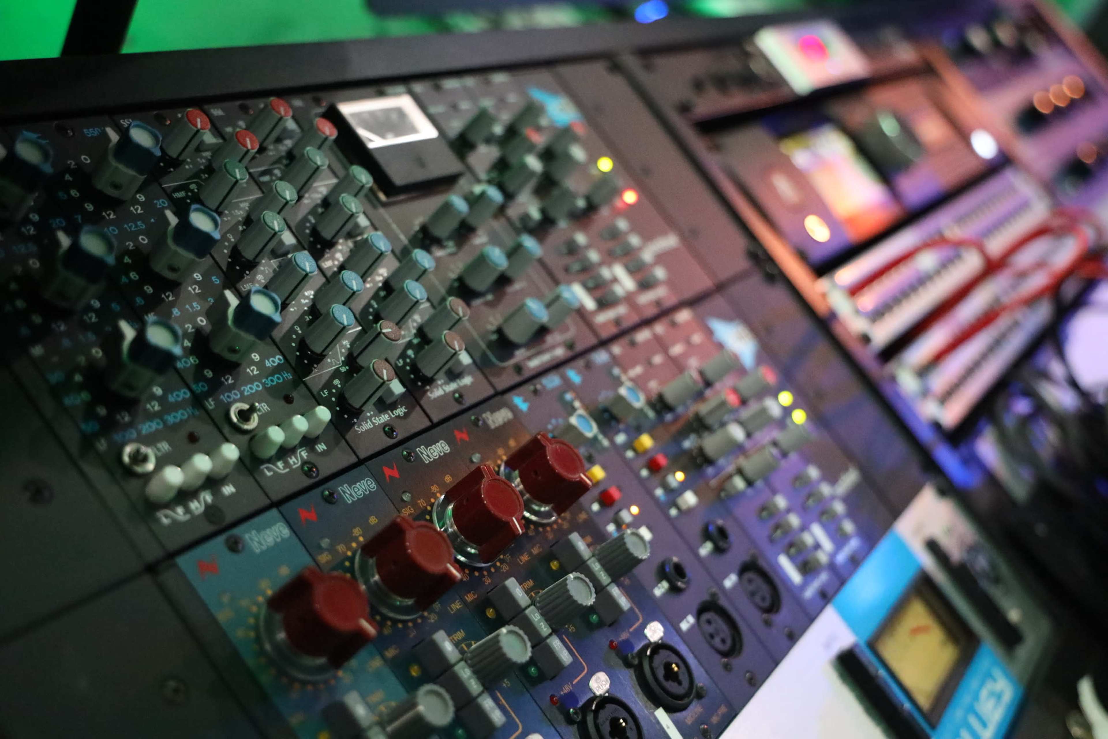 A close-up of a sound mixing console with various knobs and sliders.