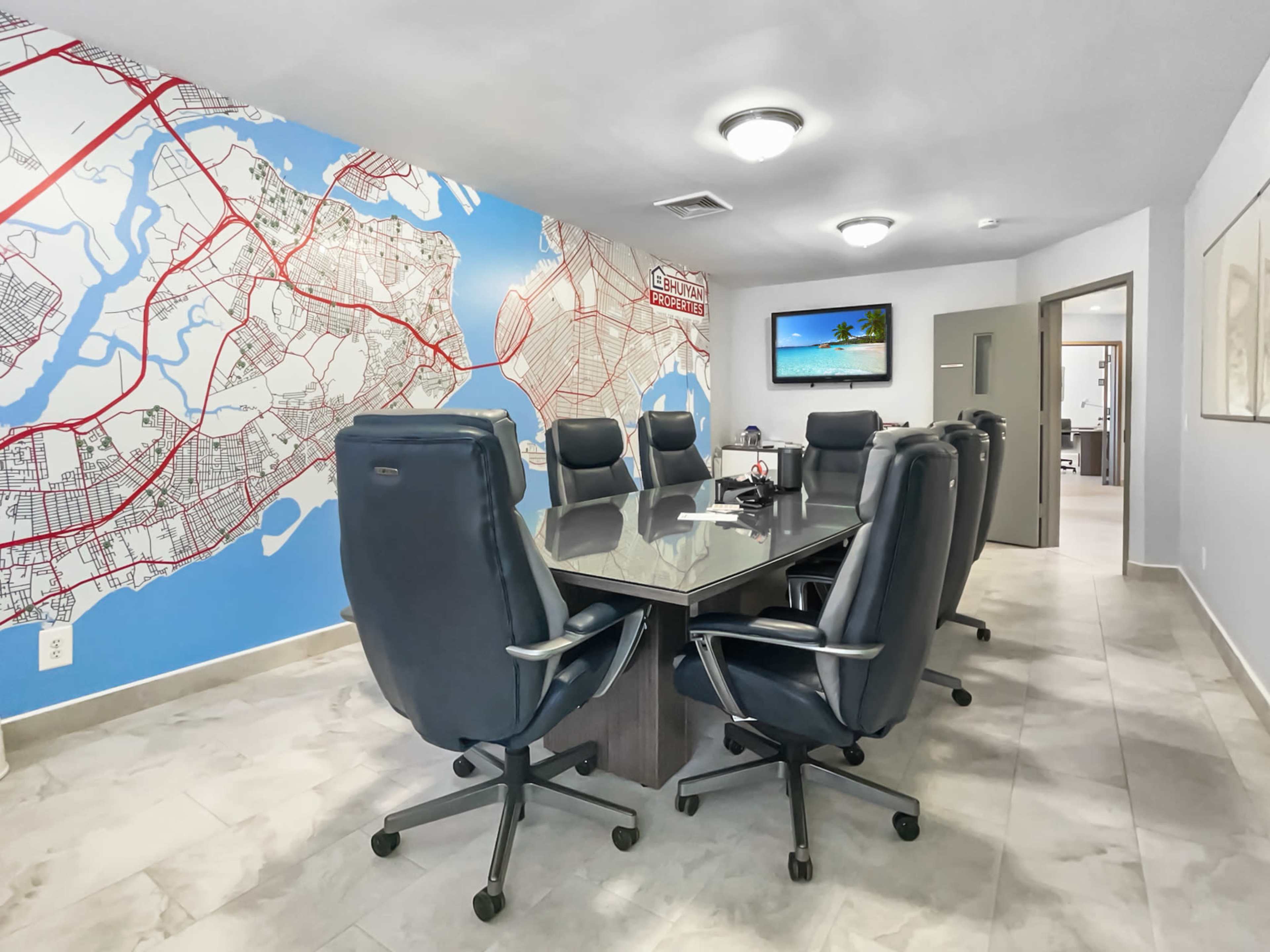 A modern conference room features a large table surrounded by comfortable chairs, against a backdrop of a map on the wall.