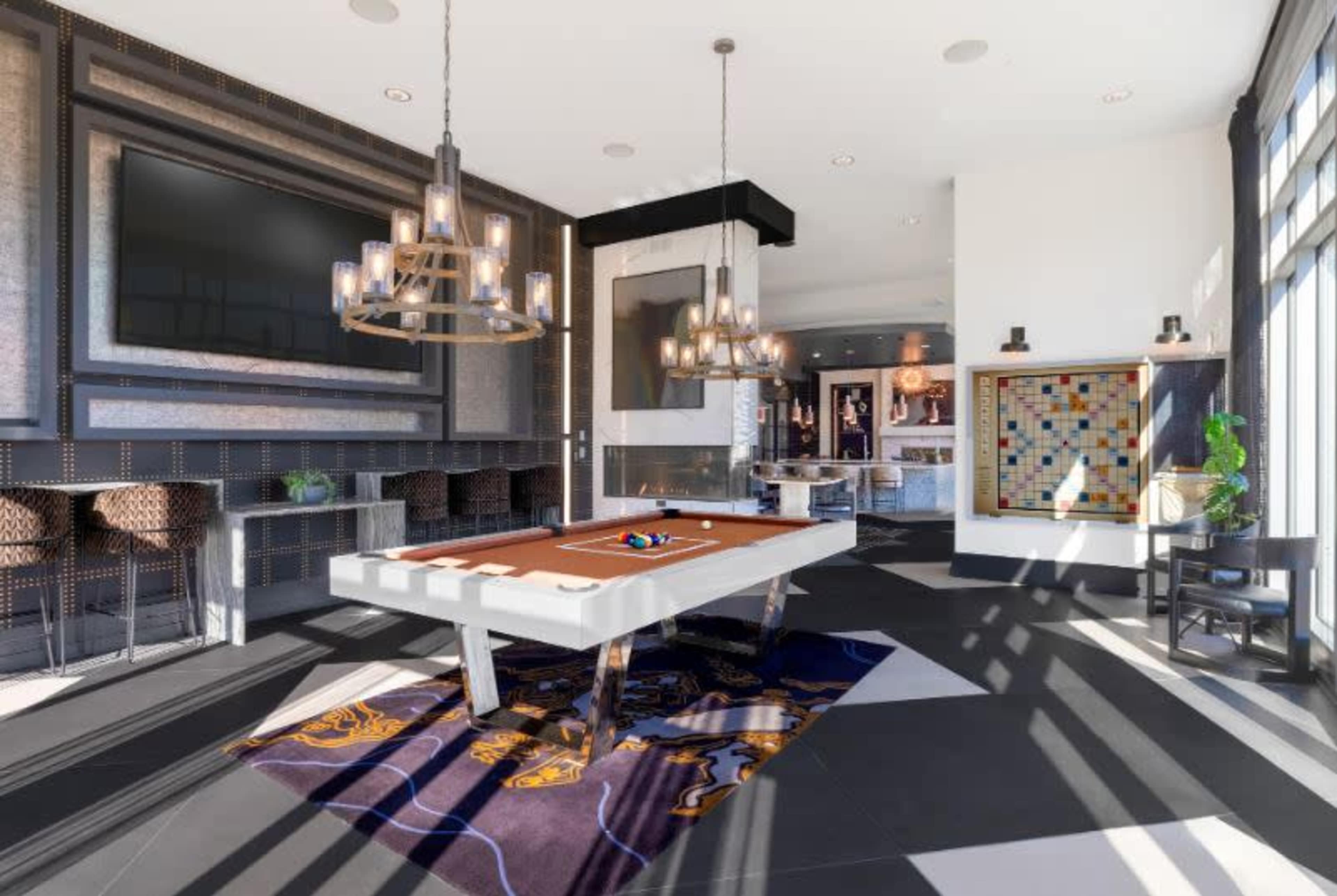 The image shows a modern recreational room featuring a billiard table, stylish lighting fixtures, and a patterned rug on a black and white tiled floor.