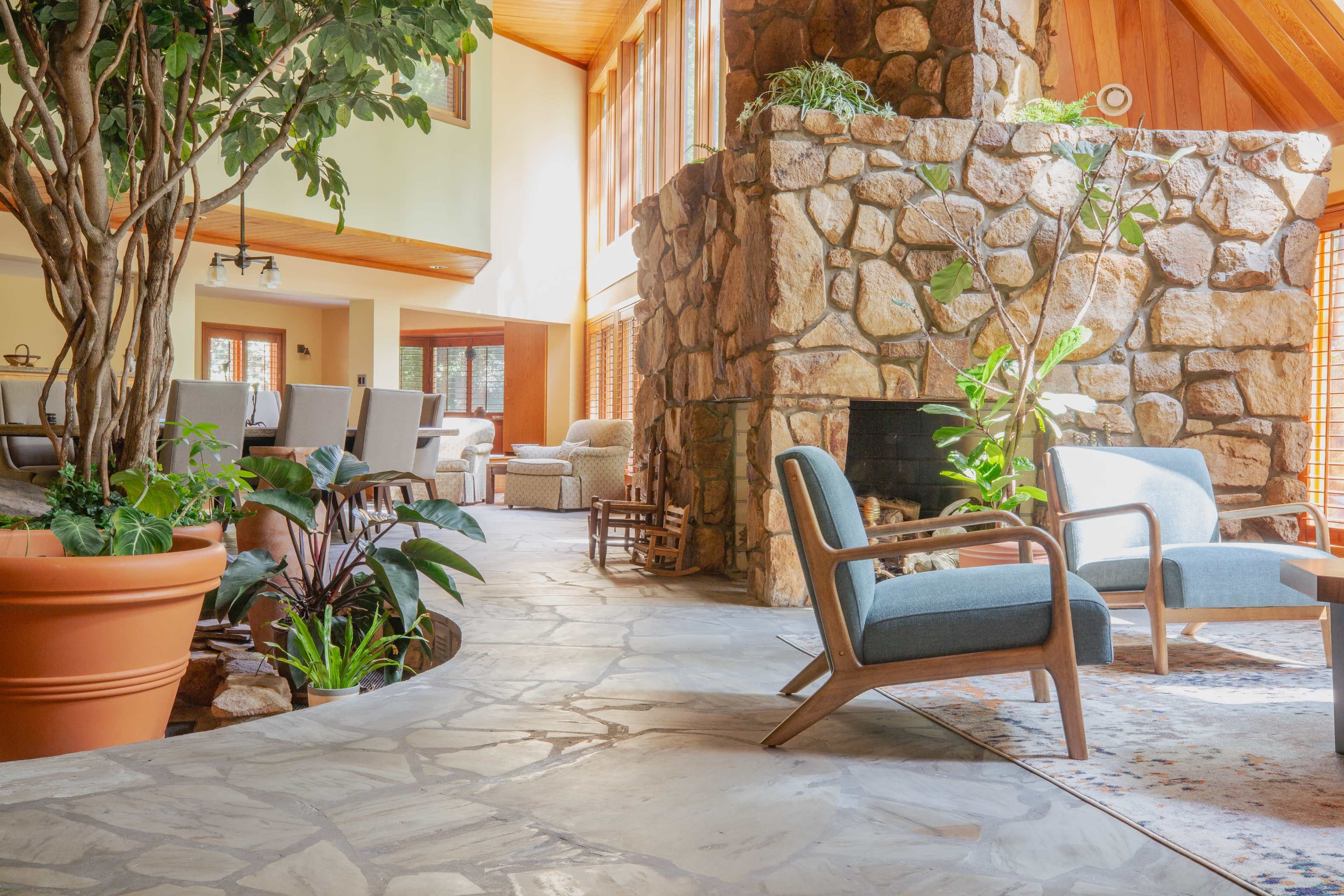 A spacious interior featuring a stone fireplace, comfortable chairs, and large windows allowing natural light to fill the room.