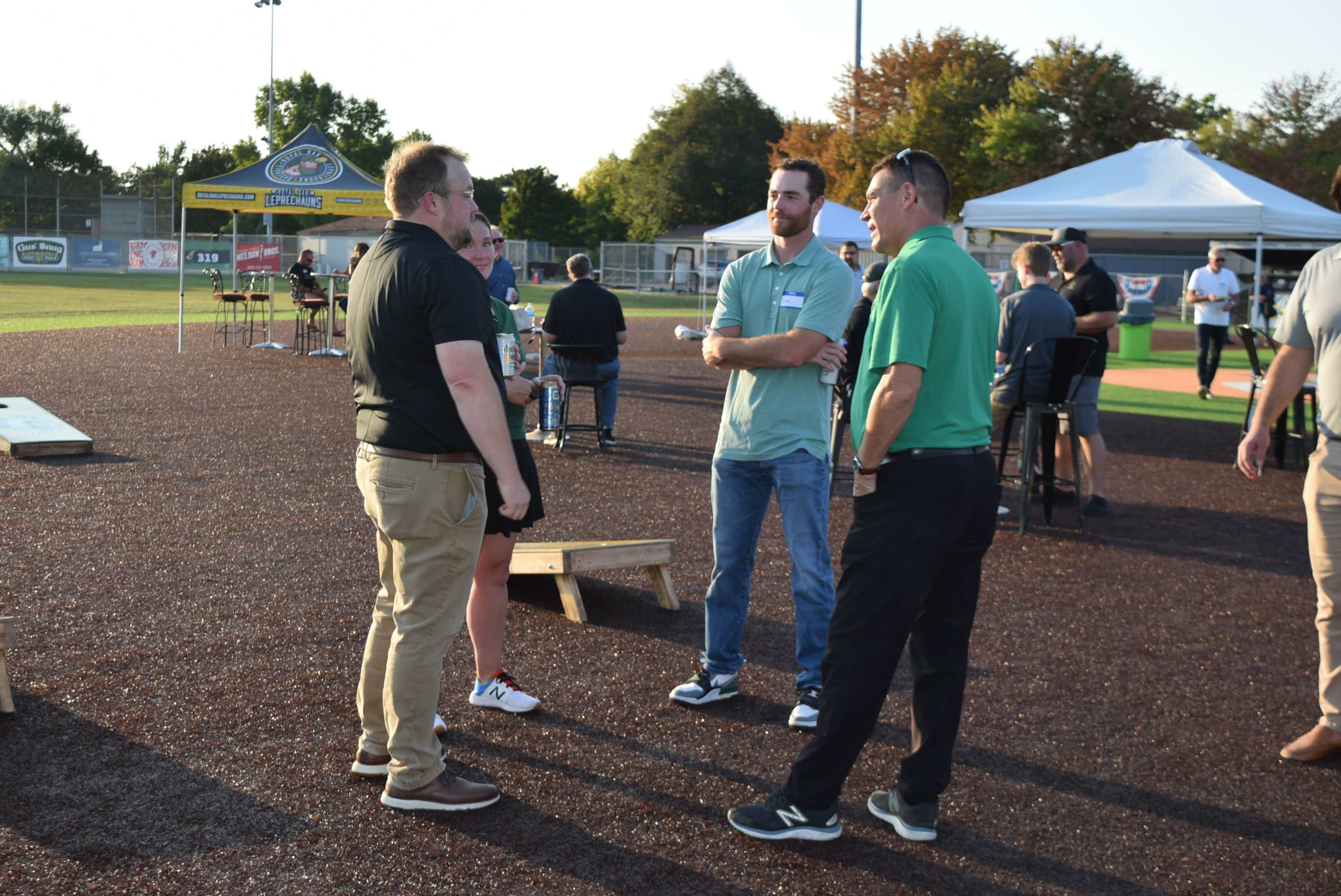 A group of four people engage in conversation on a sports field during an outdoor event.