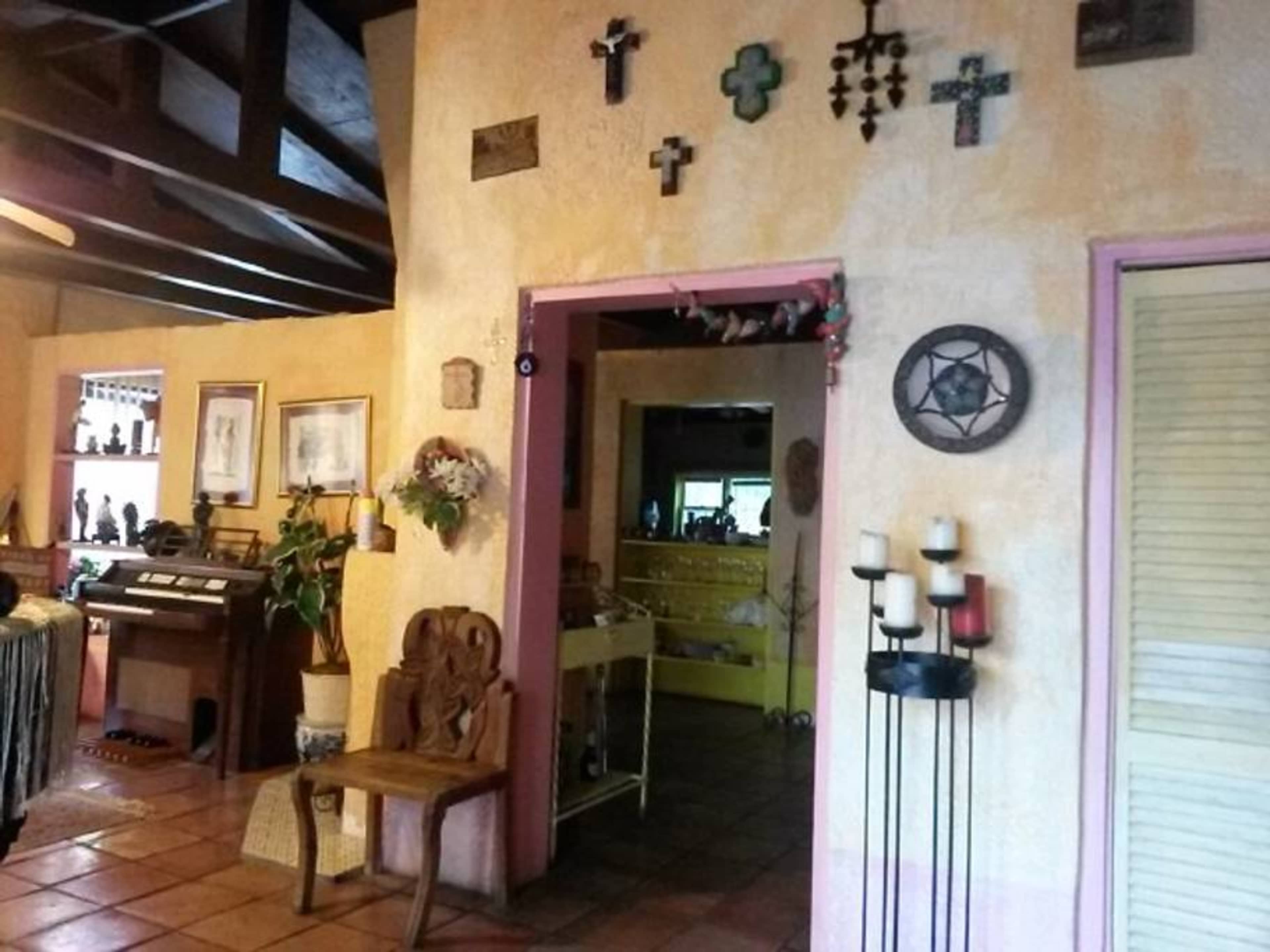 A cozy interior with textured yellow walls, wooden beams, and various crosses and decorative items on display.
