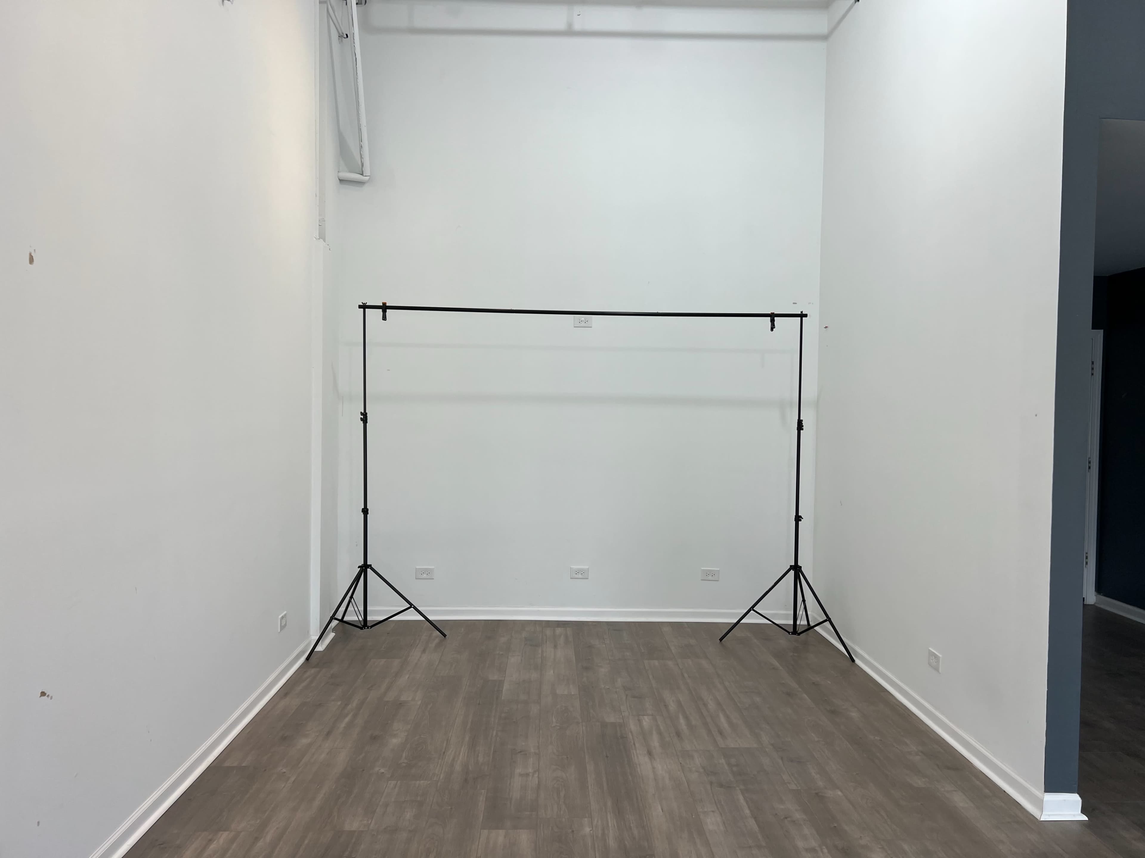 An empty room with white walls and a backdrop stand positioned in the center.