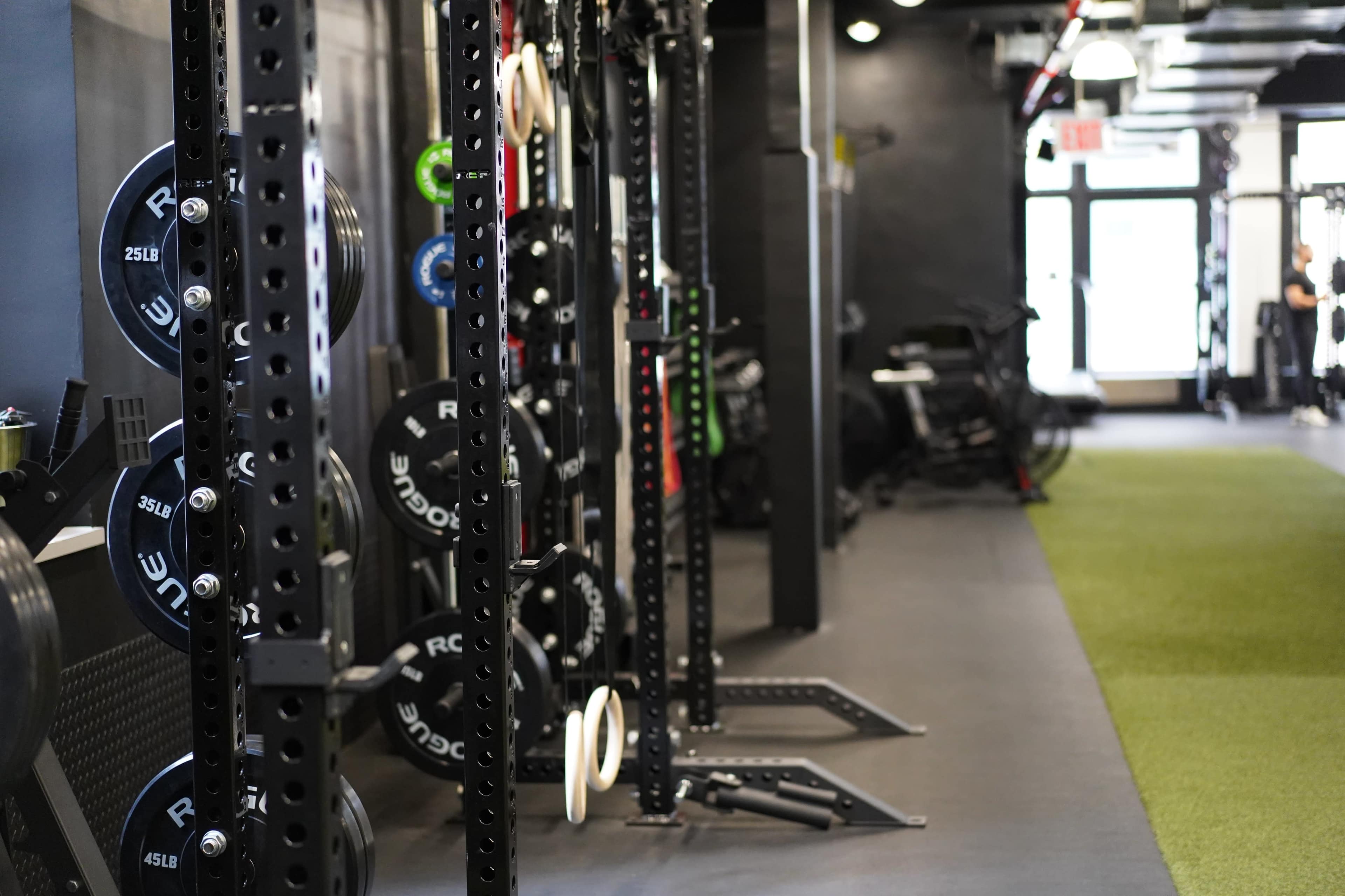 A row of weightlifting equipment and racks in a modern gym interior.