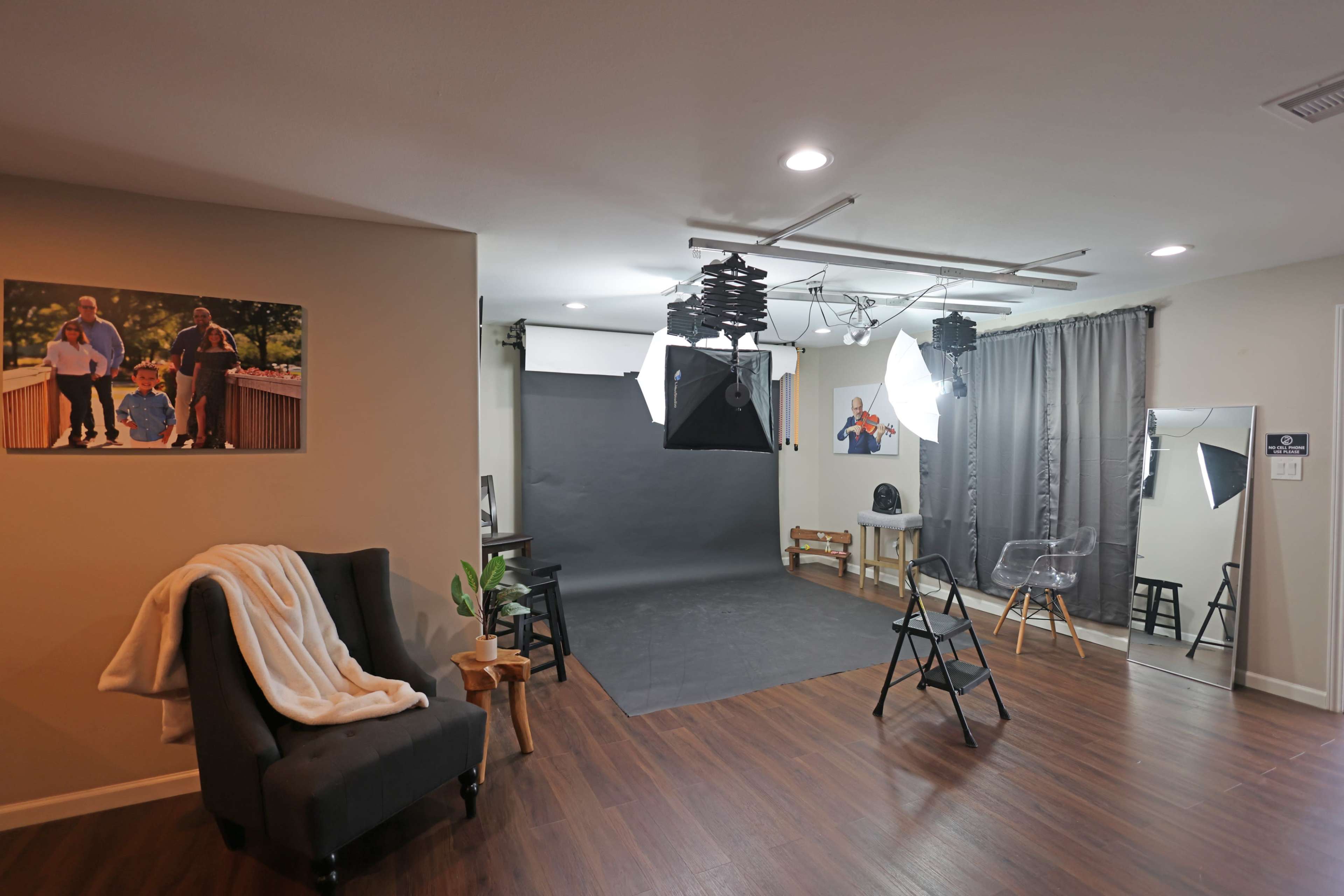 A photography studio equipped with lighting, a backdrop, and a seating area with a chair and a small table.