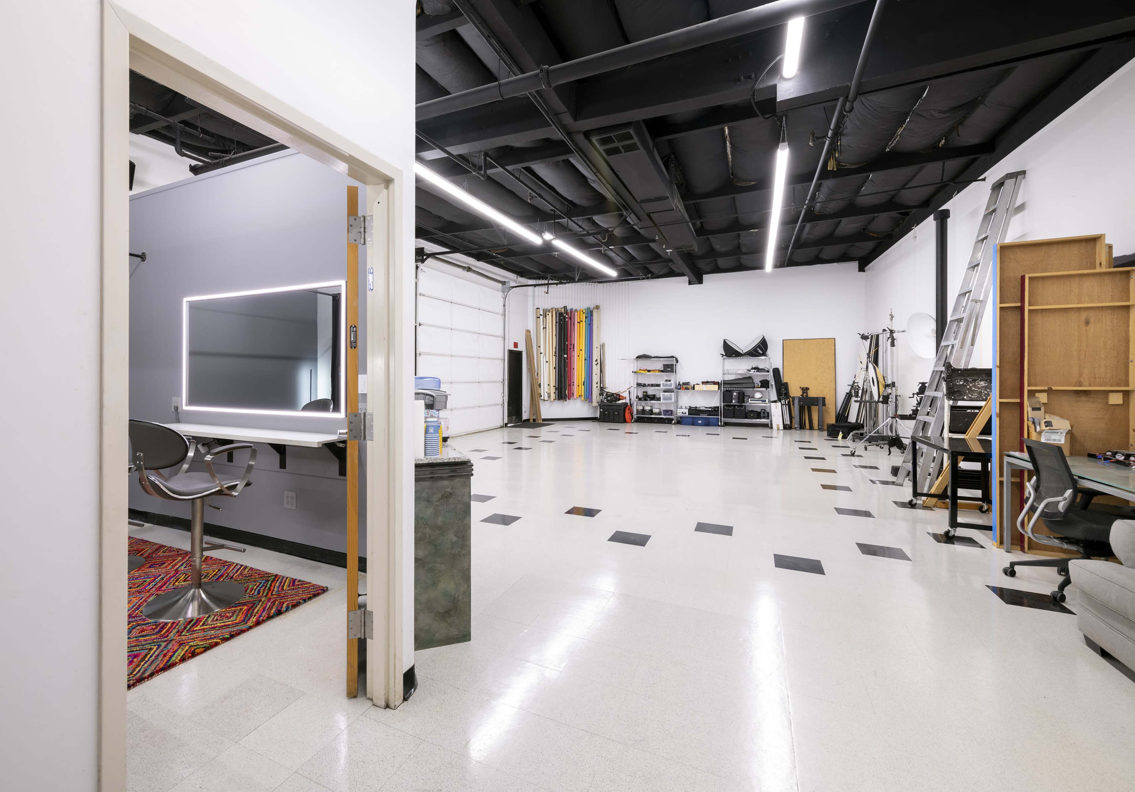 A spacious studio with high ceilings, various equipment, and a partially visible entrance.