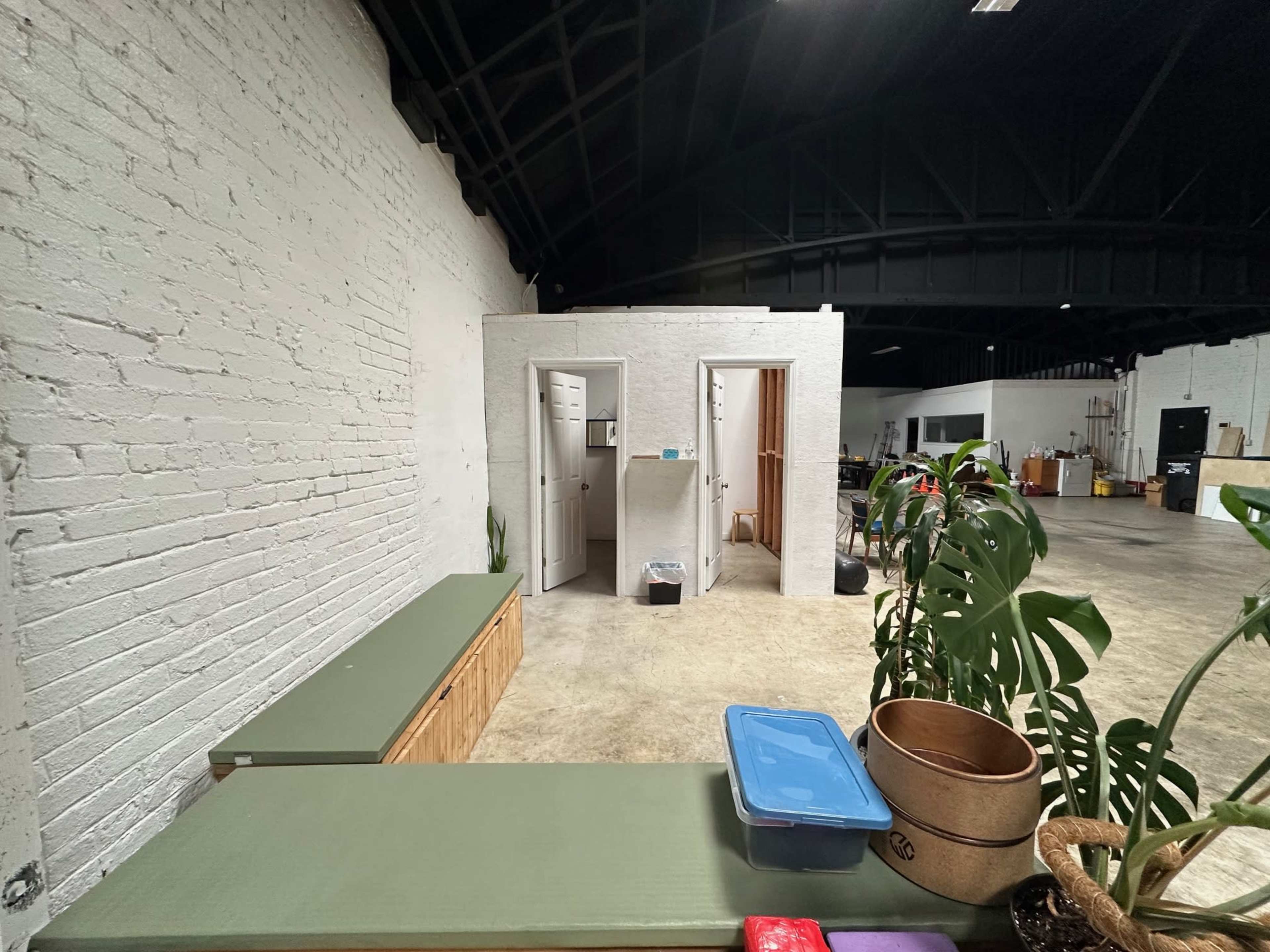 The image shows an industrial-style interior with a white brick wall, a wooden counter, and two restroom doors at the back.