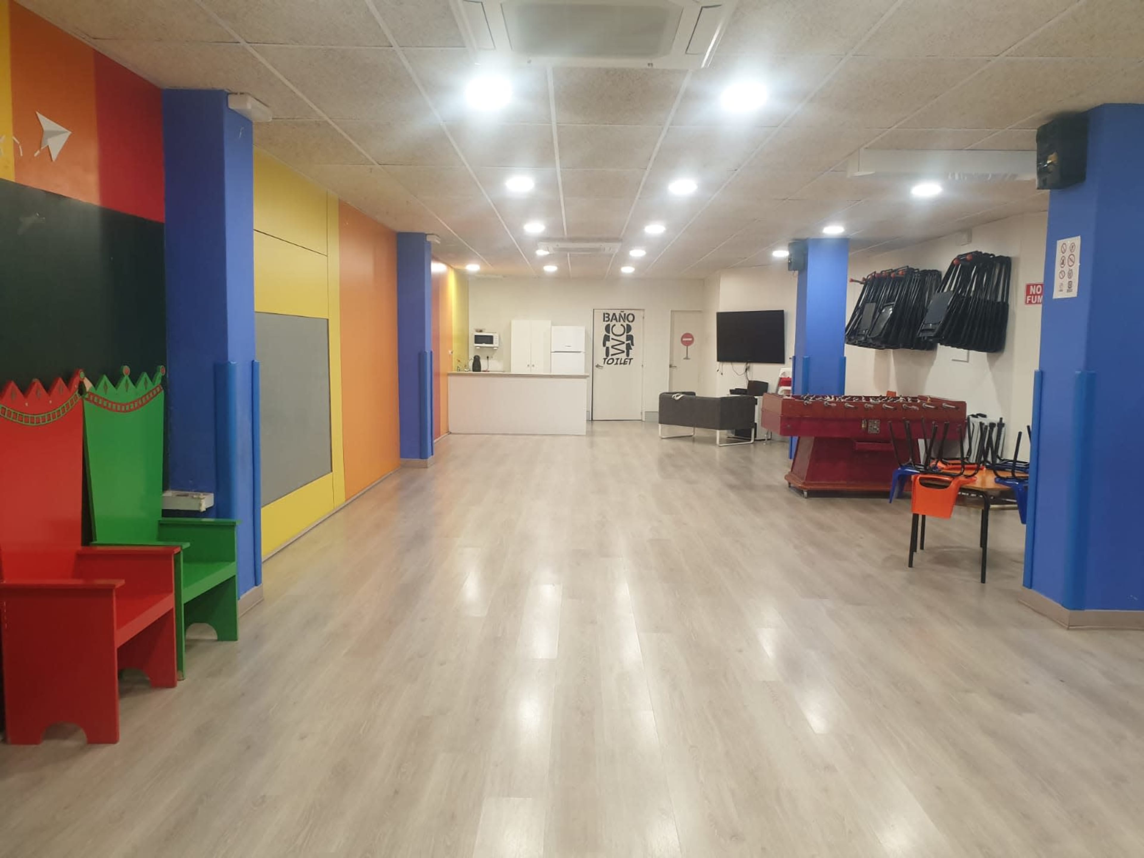 A spacious room with colorful walls, a kitchenette area, and a foosball table against one side.