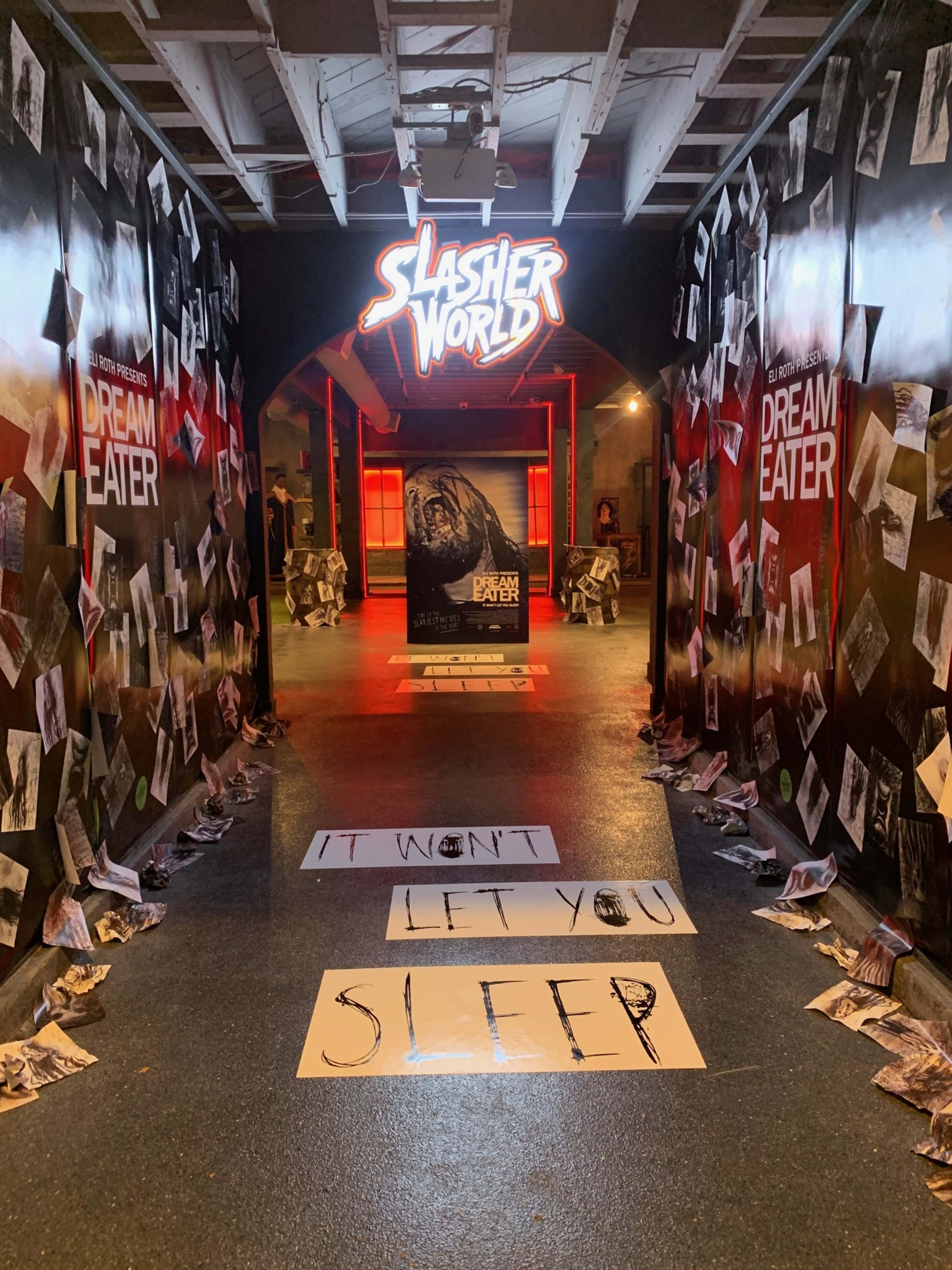 The image depicts a dimly lit hallway adorned with posters and eerie imagery, leading to an entrance labeled "Slasher World."