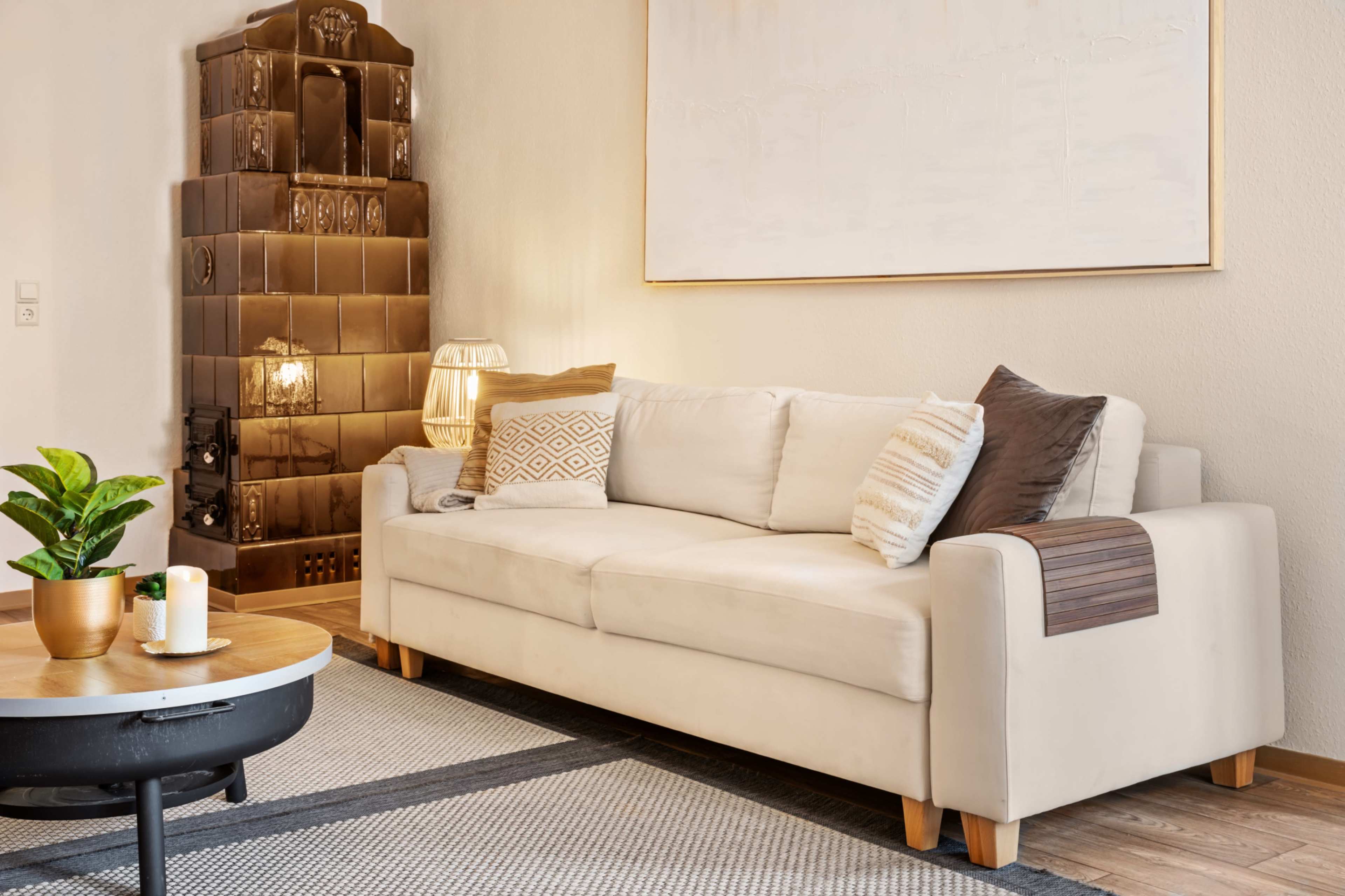The living room features a light-colored sofa with decorative pillows, a round coffee table, and a textured rug, alongside a decorative wall and a modern lamp.