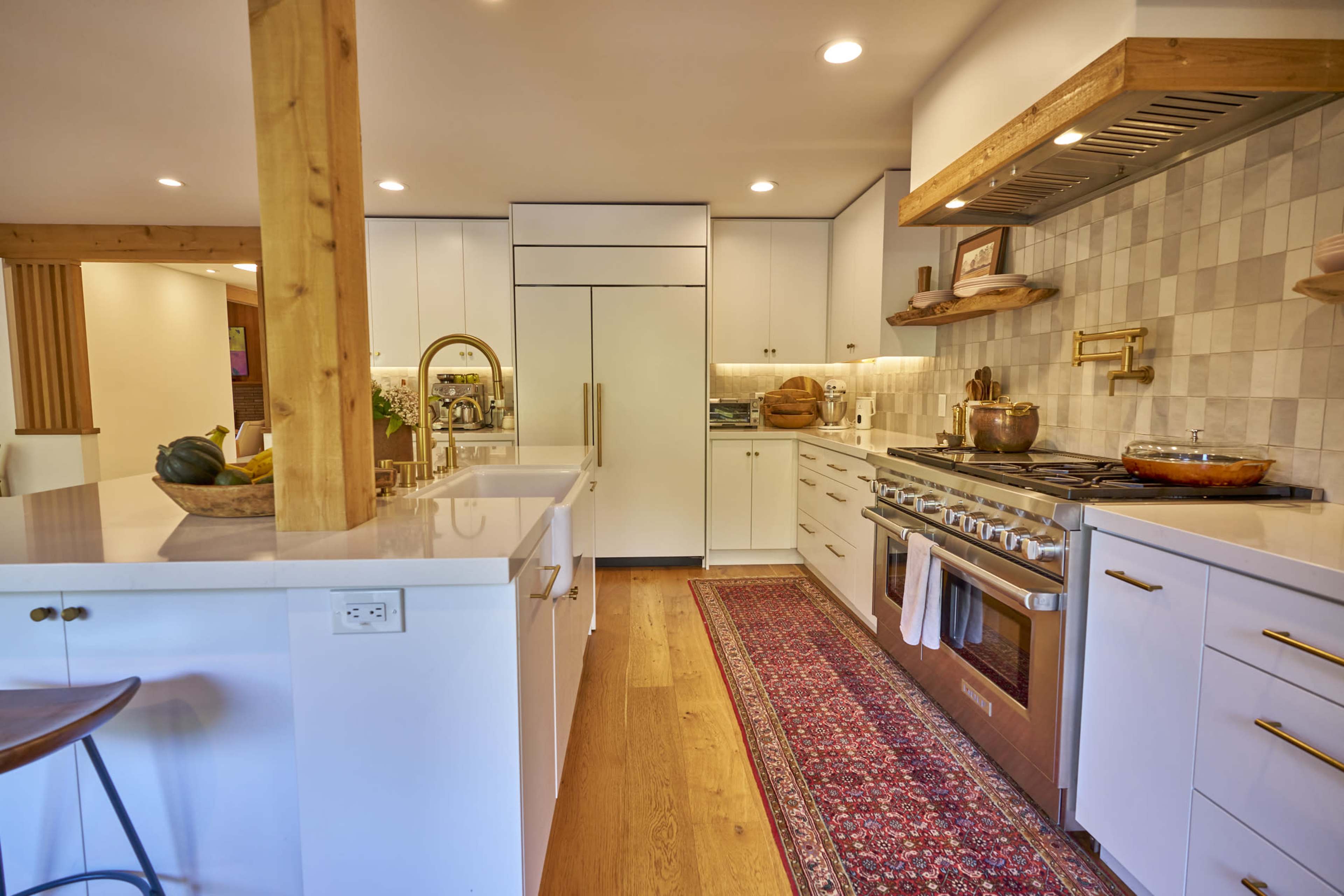A modern kitchen features white cabinetry, a large stove with a copper pot, and a central island with bar seating.