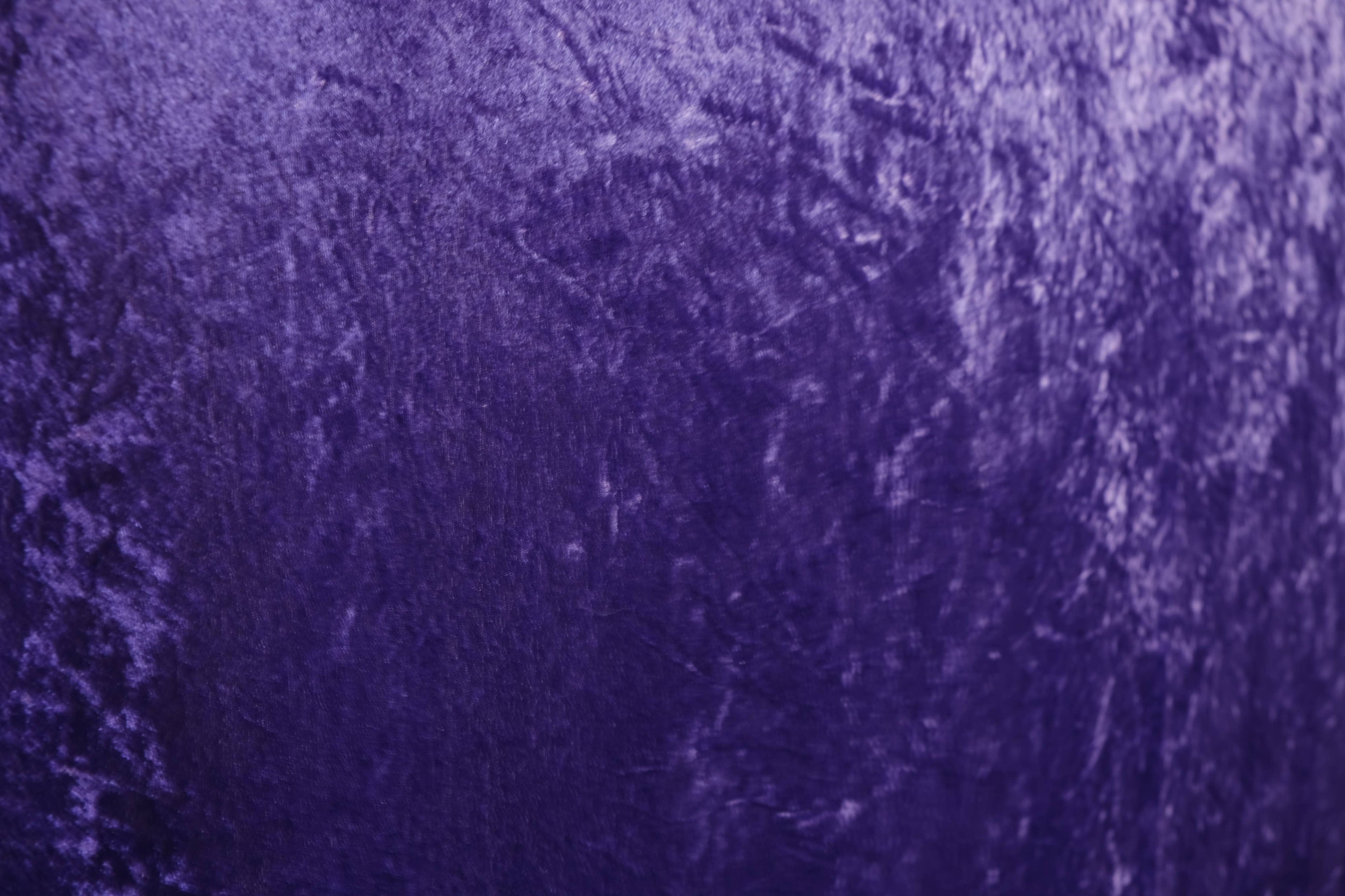 A textured surface of deep purple fabric.