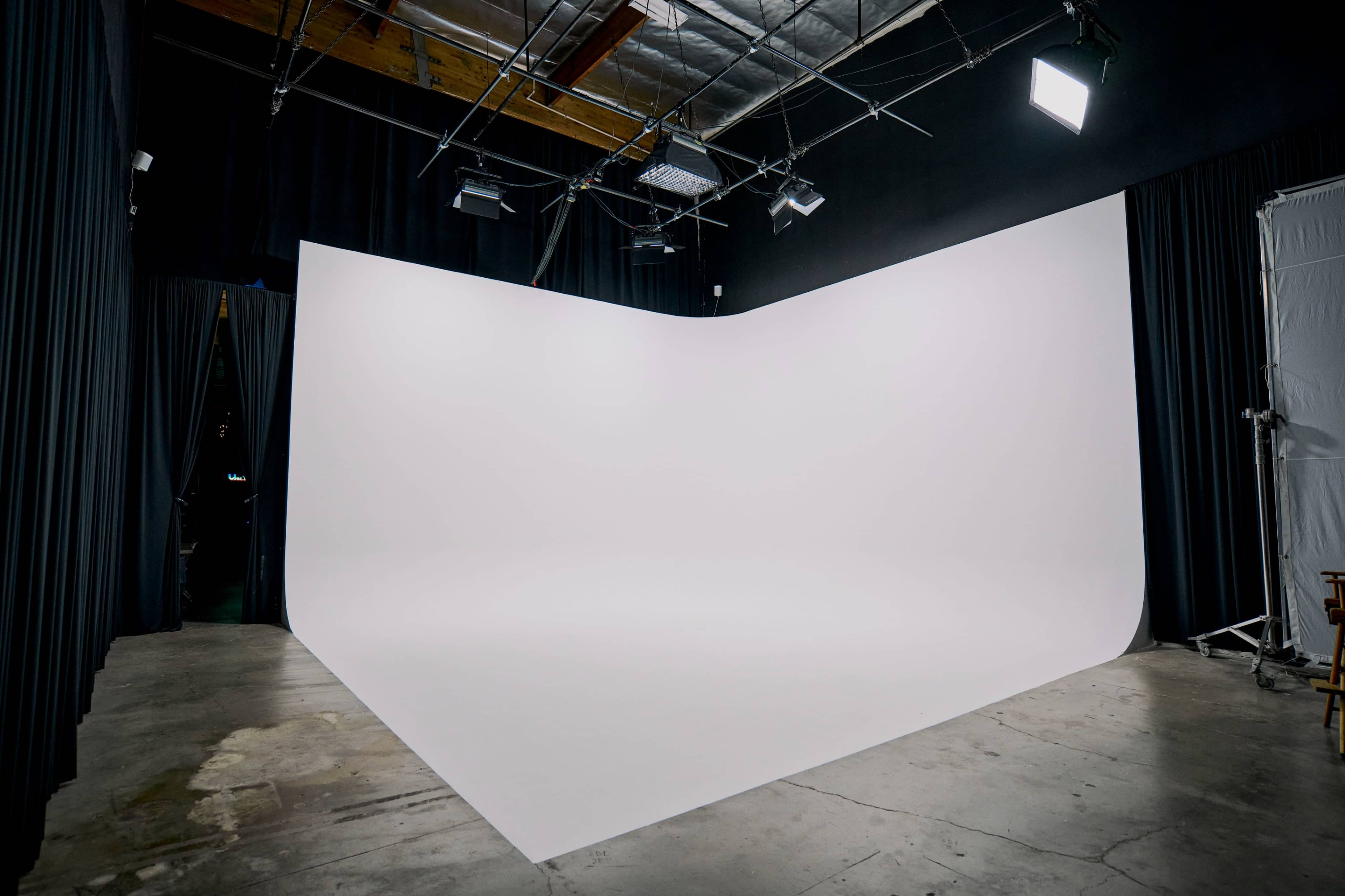 A photography studio with a curved white backdrop and dimly lit surroundings.