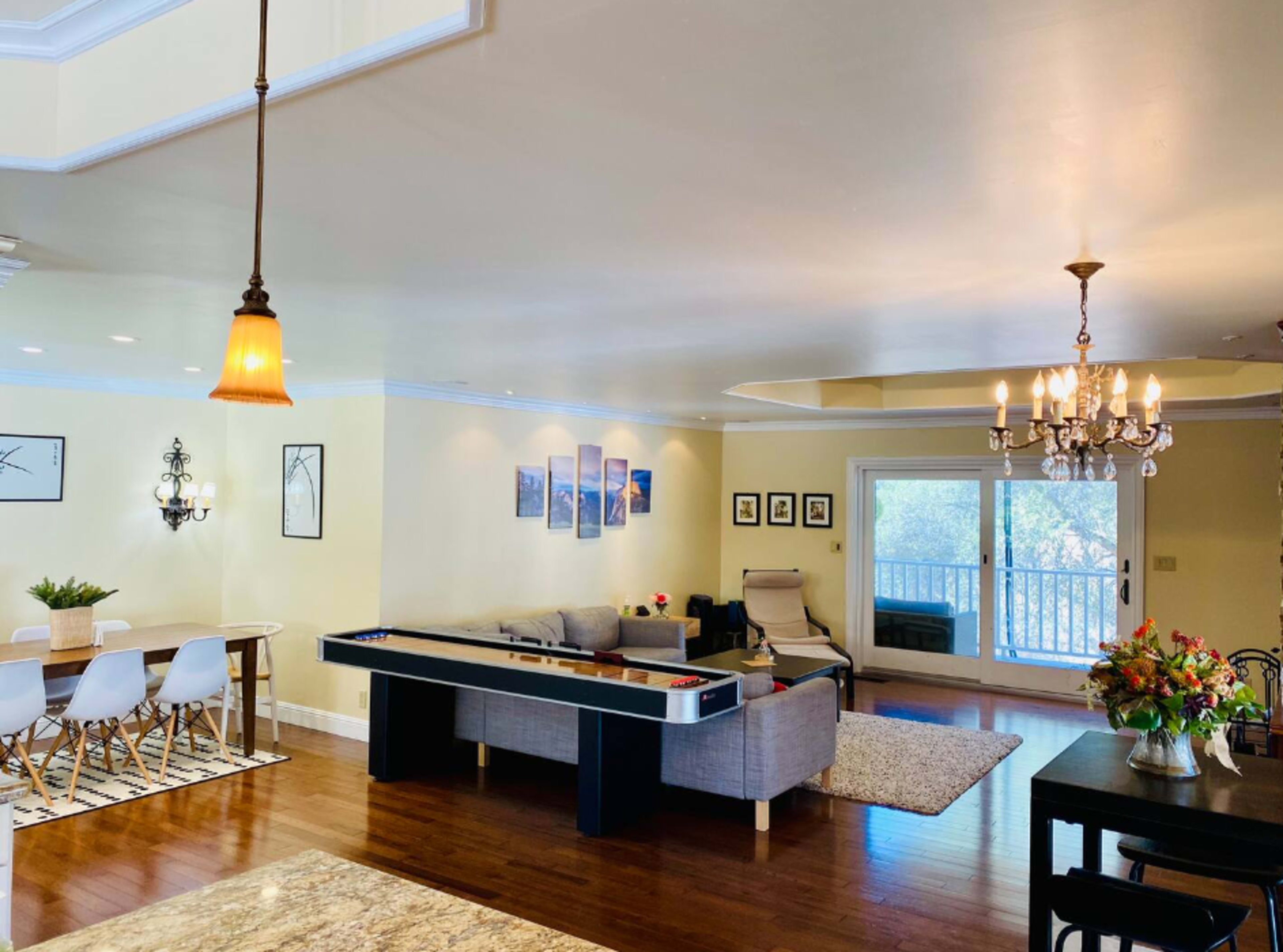 The image shows a spacious living area featuring a couch, dining table, and large windows with a view.