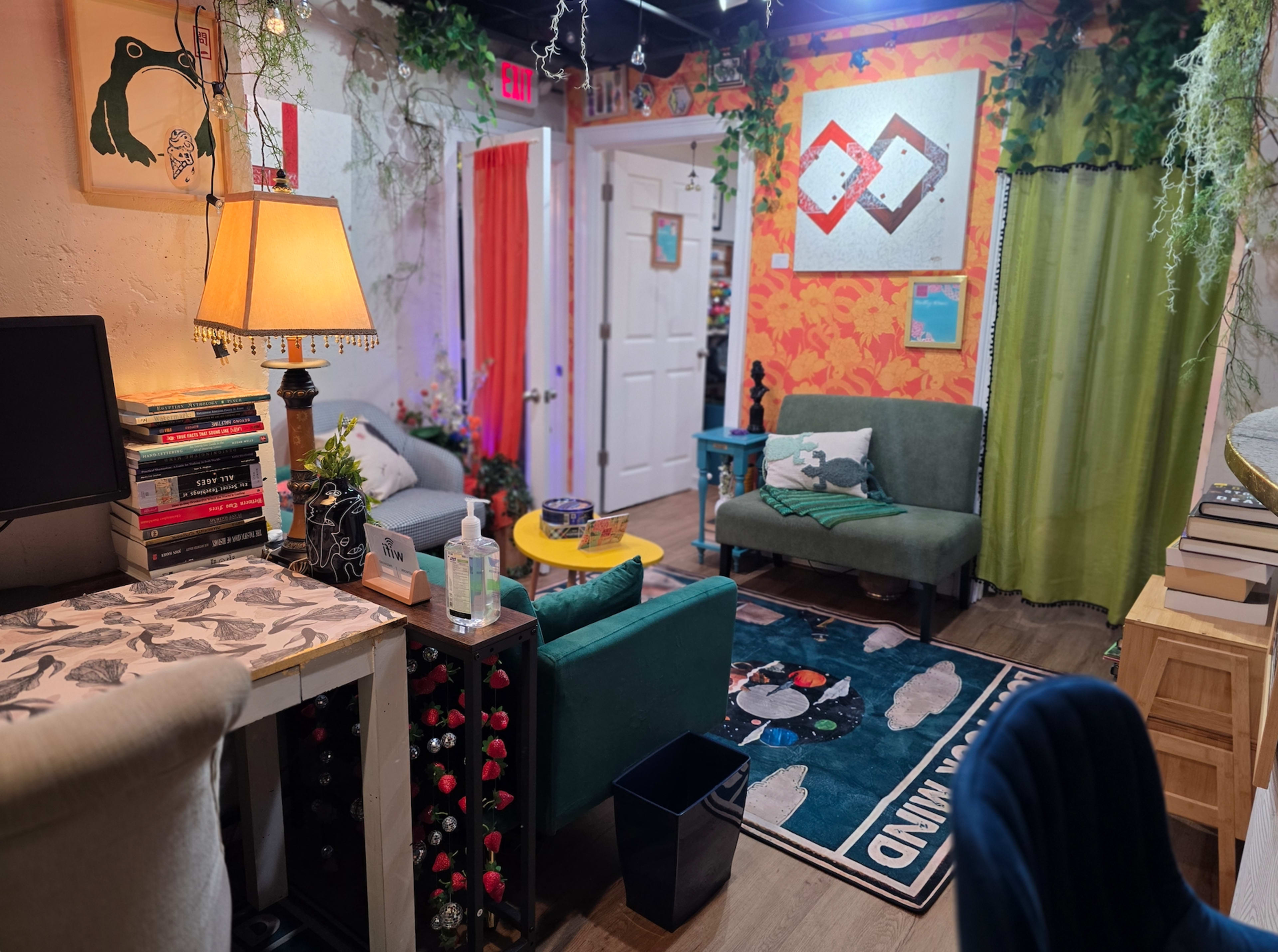 The image depicts a colorful, eclectic living space featuring two green couches, a yellow coffee table, a lamp, and decorative plants.