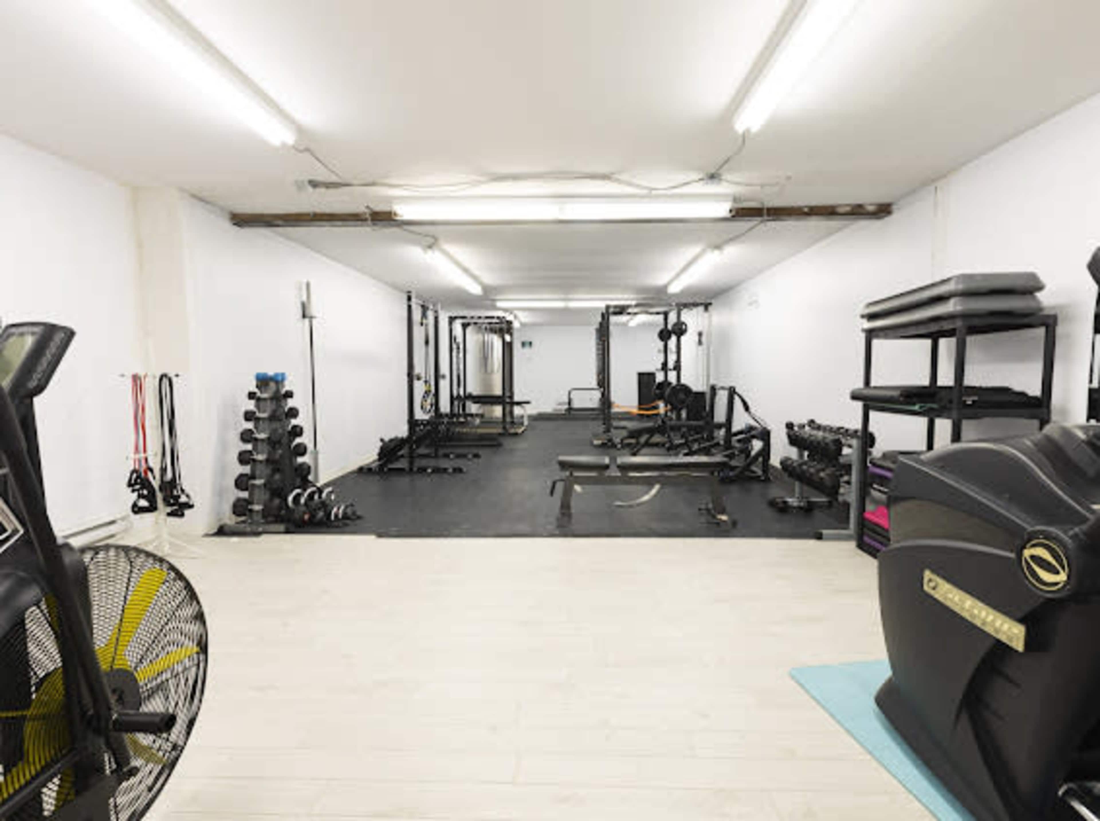 A spacious gym equipped with various workout machines, free weights, and storage racks in a well-lit room.